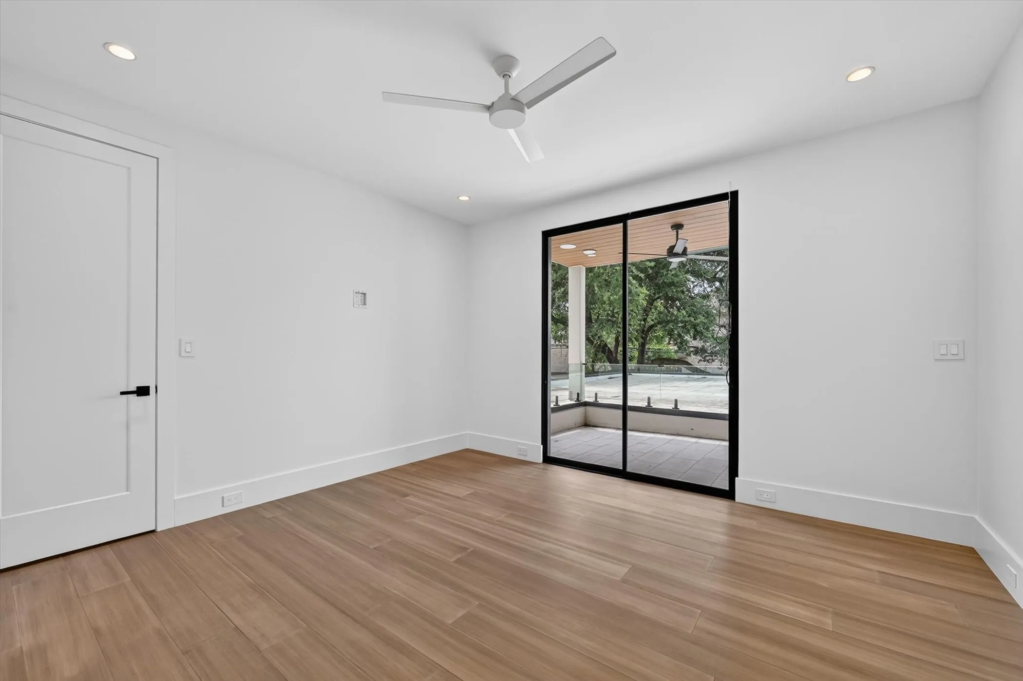 Bright interior space featuring wood-finish flooring, a modern ceiling fan, and recessed lighting