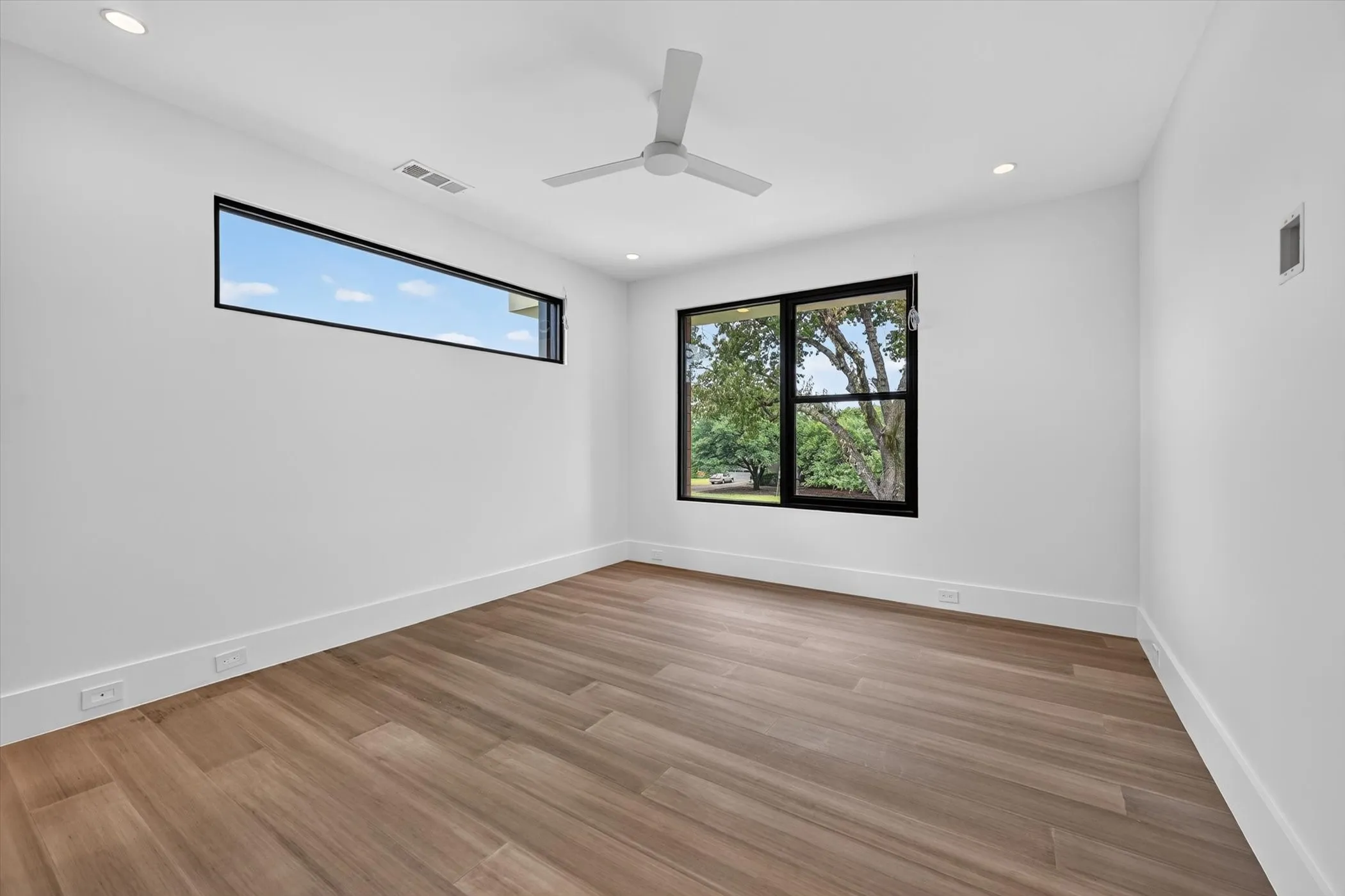 Wood-finish flooring, white walls, and recessed lighting