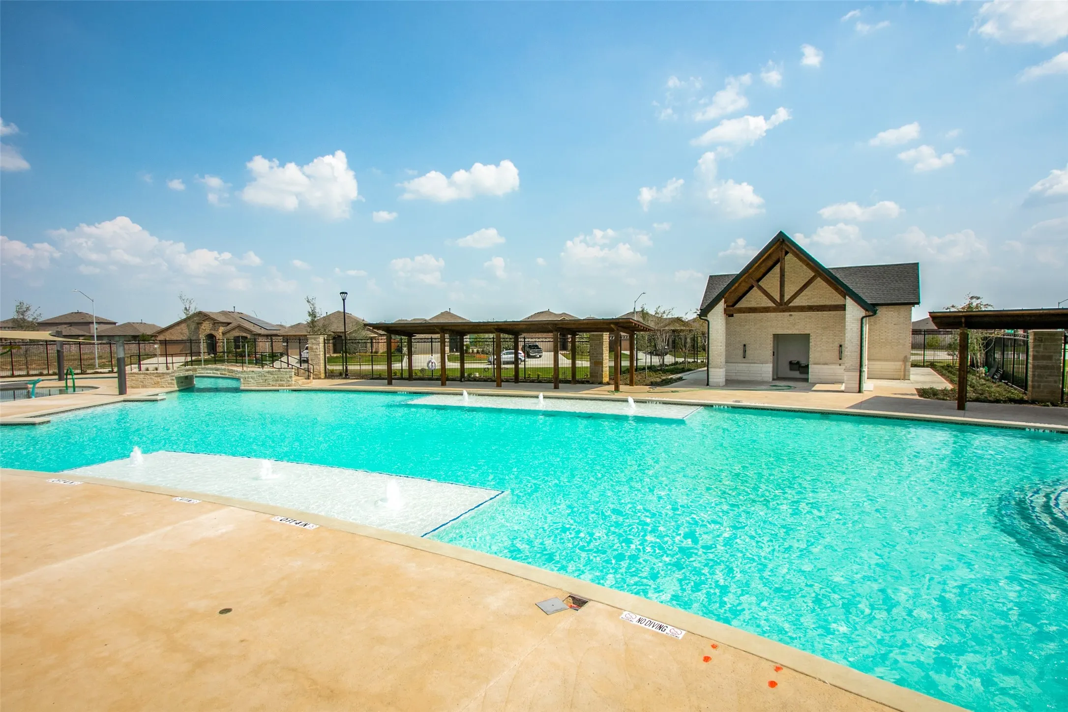 Community swimming pool featuring a large aquatic area with integrated shallow tanning ledges and water features