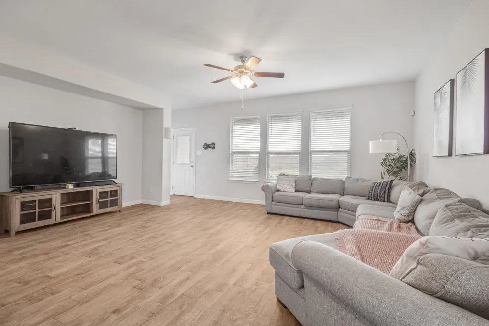 Spacious living area featuring wood-finish flooring and light-toned walls
