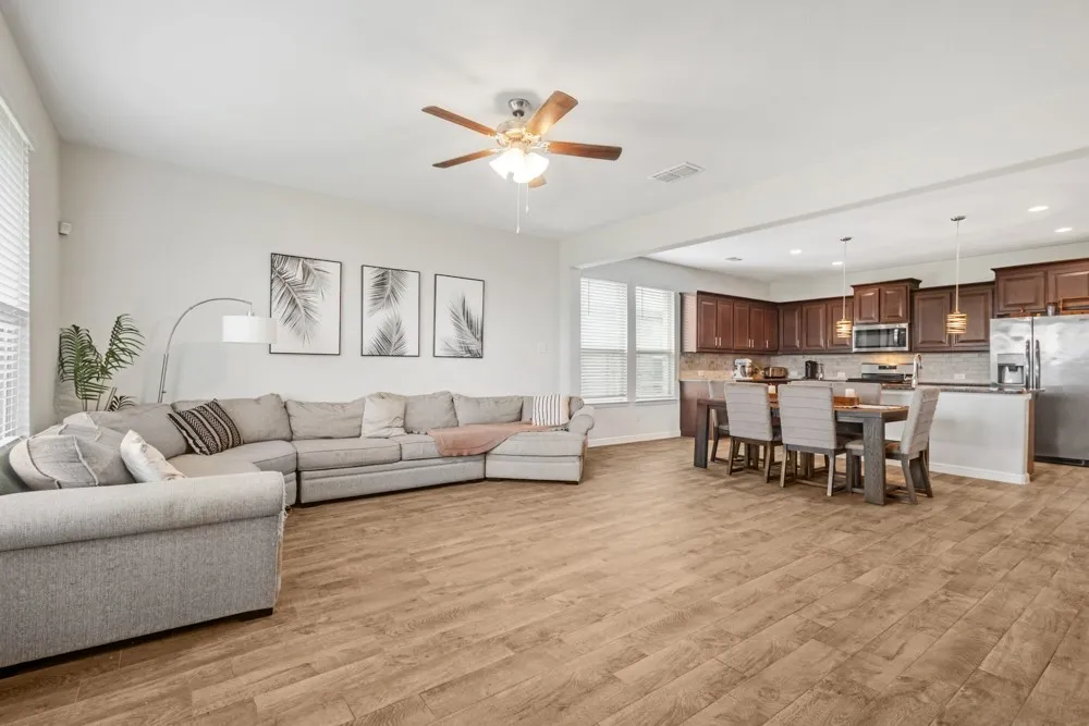Open-concept living space featuring wood-finish flooring, a contemporary ceiling fan, recessed lighting, and ample natural light from multiple windows