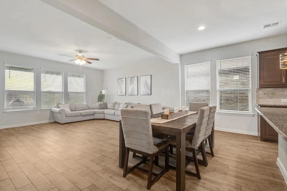 Open-concept interior featuring wood-finish flooring, recessed lighting, and multiple windows with blinds