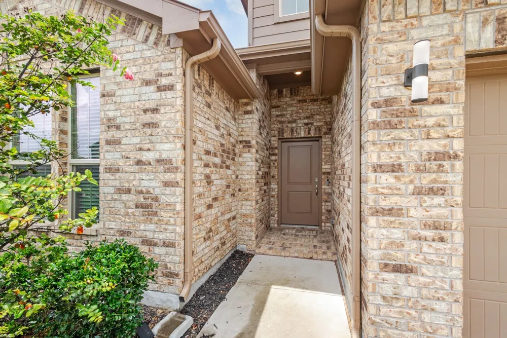 Brick facade entry featuring a covered porch, recessed entryway lighting, a paneled front door, and an exterior wall​​‌​​​​‌​​‌‌​‌‌​​​‌‌​‌​‌​‌​​​‌​​ sconce