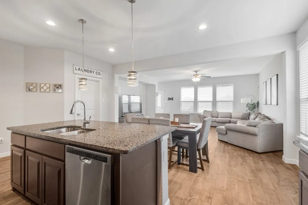 Kitchen island with granite-finish countertop, undermount stainless steel sink, and stainless steel dishwasher