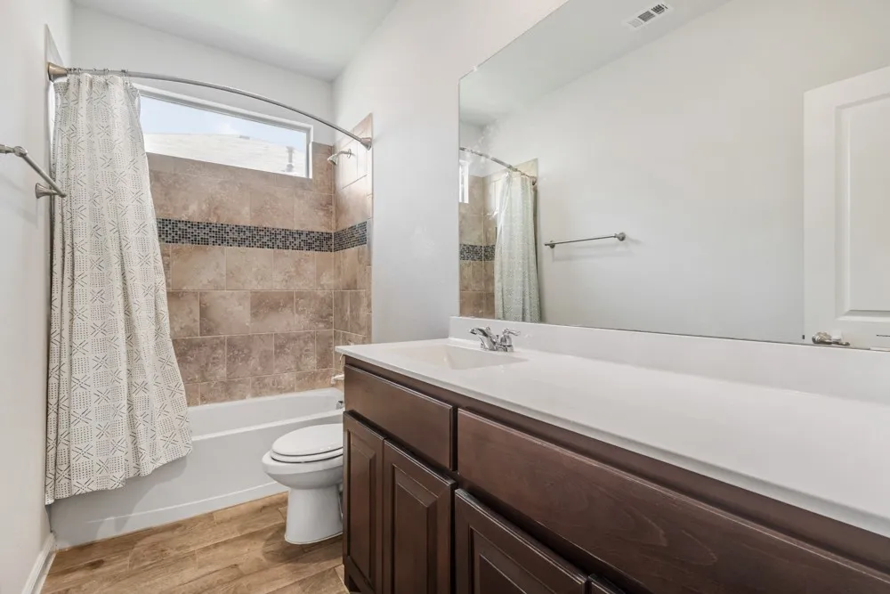 Bathroom featuring a dark wood-finish vanity, white countertop, integrated sink, and a large wall-mounted mirror