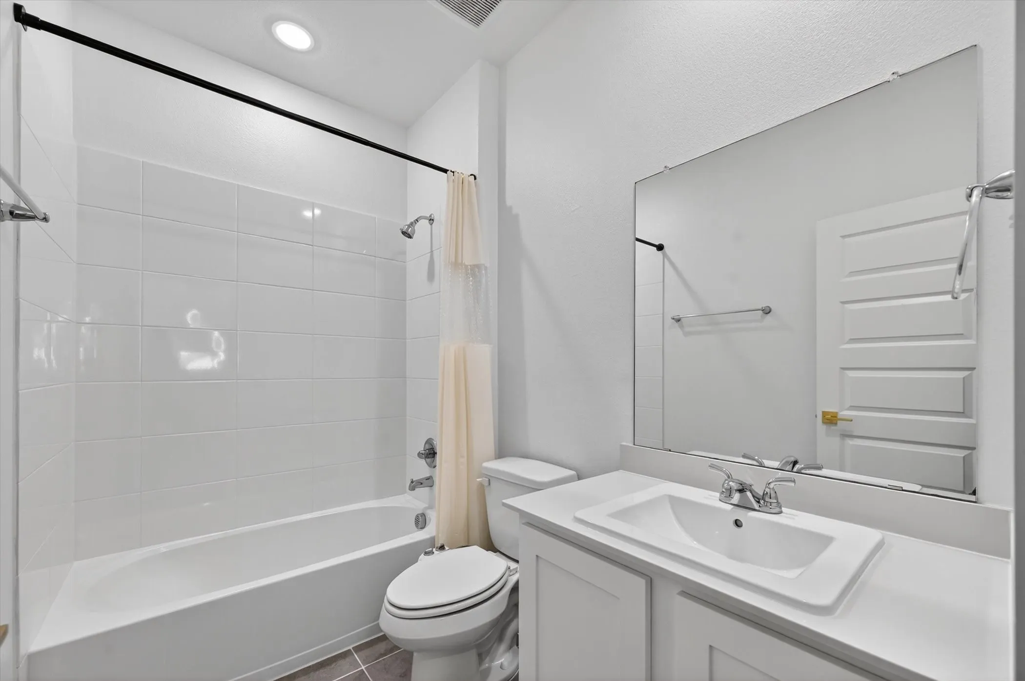 Bathroom featuring a white vanity with an integrated sink, polished chrome faucet, and a large wall-mounted mirror