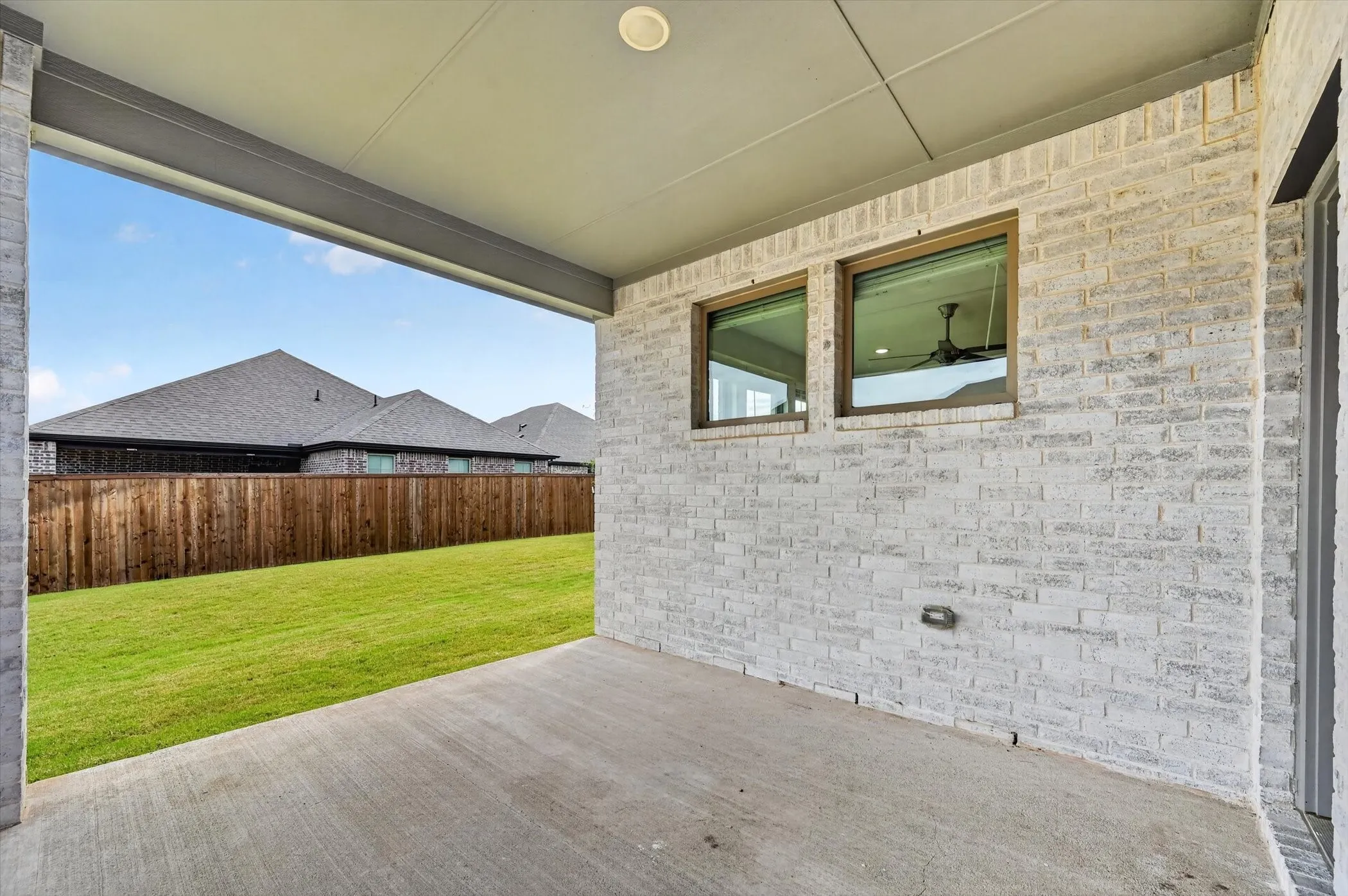 Covered patio featuring a concrete slab and painted brick exterior