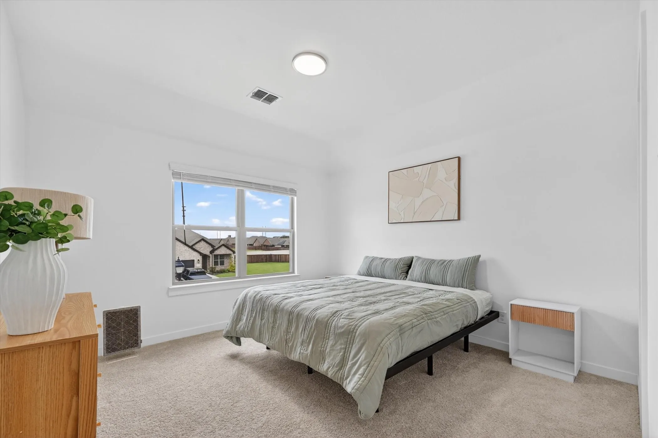 Bright bedroom featuring a large window, neutral carpeting, and recessed lighting