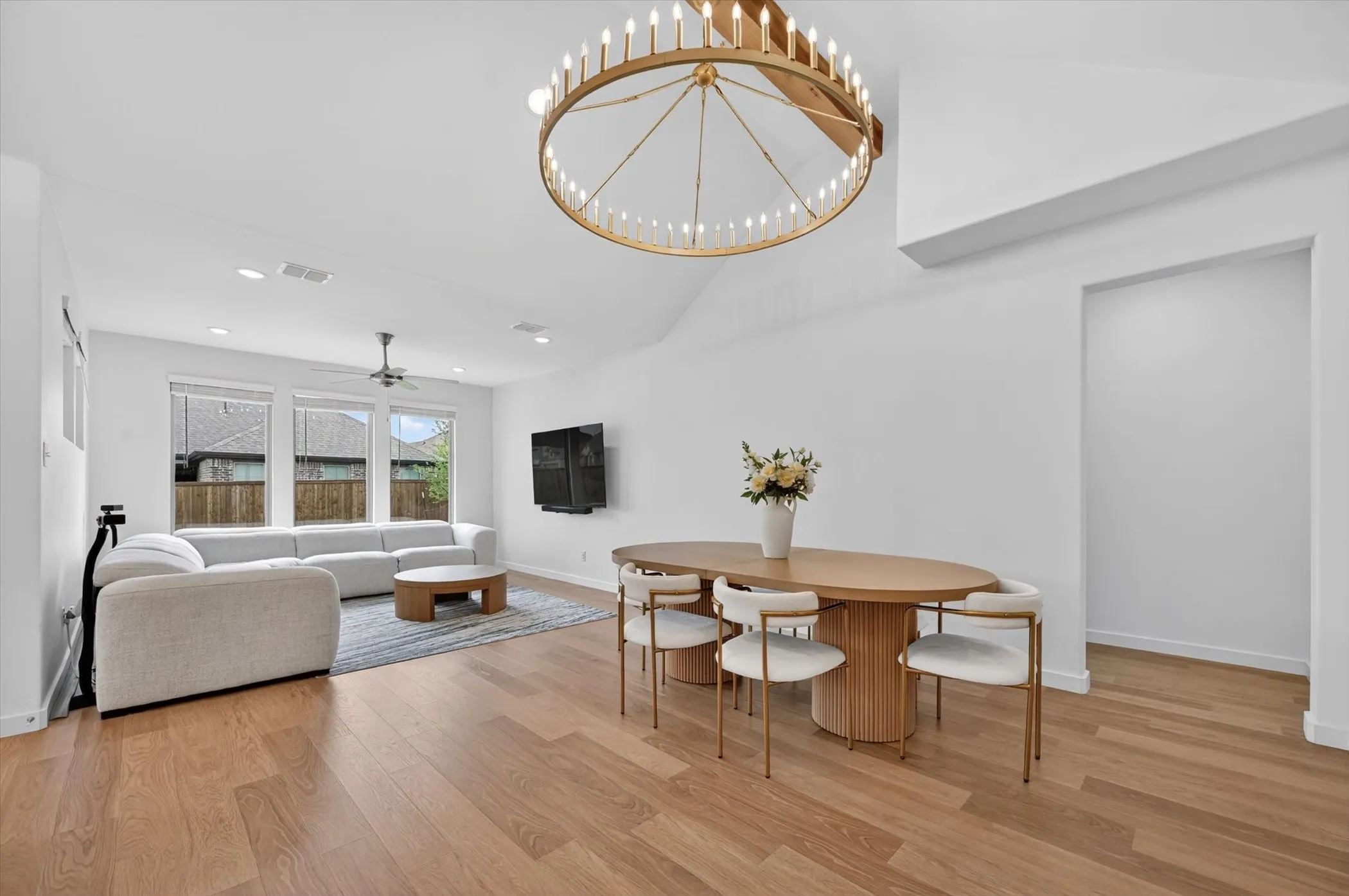 Open-concept living and dining area featuring wood-finish flooring, a vaulted ceiling, and recessed lighting