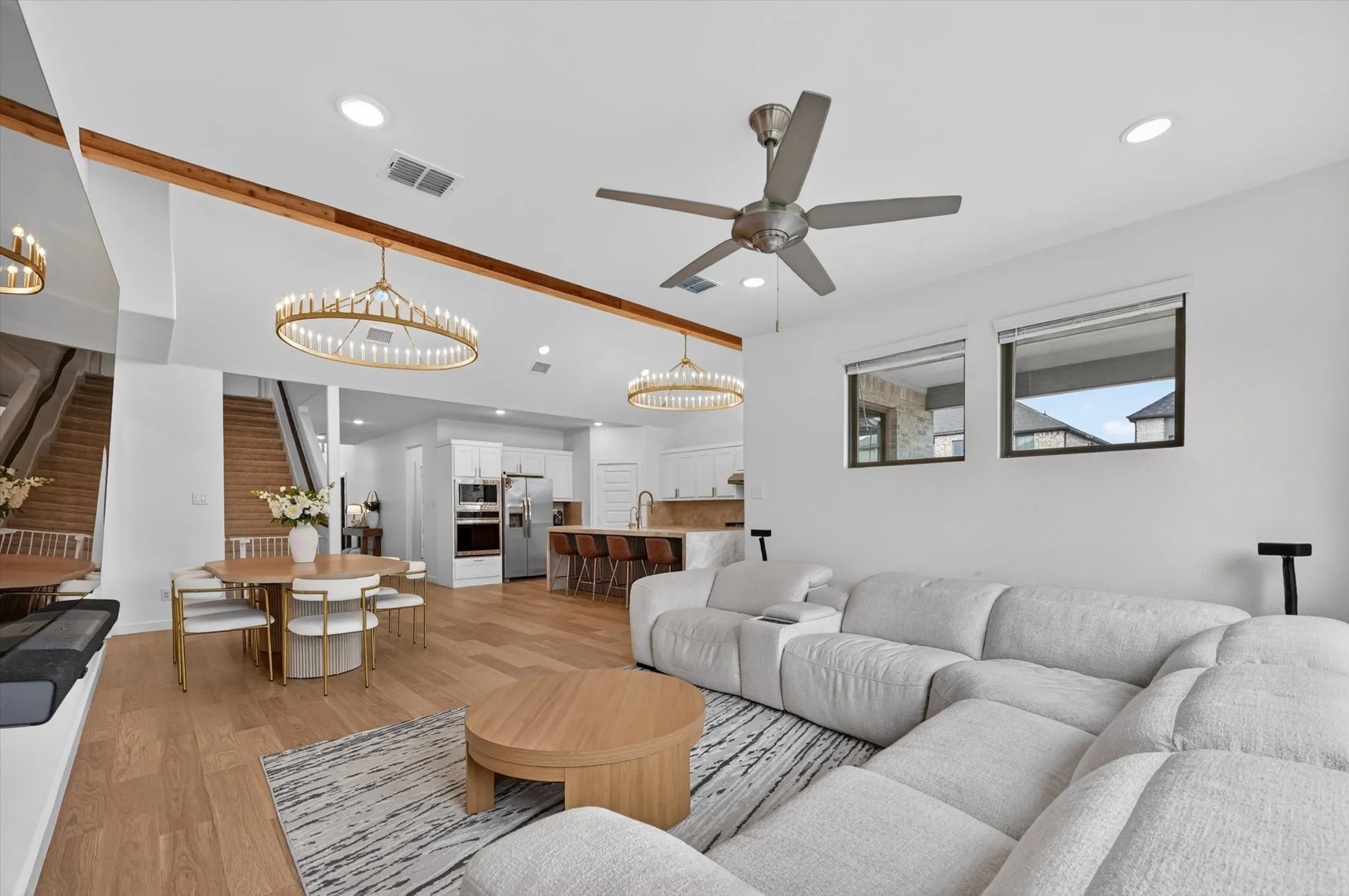 Open-concept living area with light wood-finish flooring, recessed lighting, and a contemporary ceiling fan