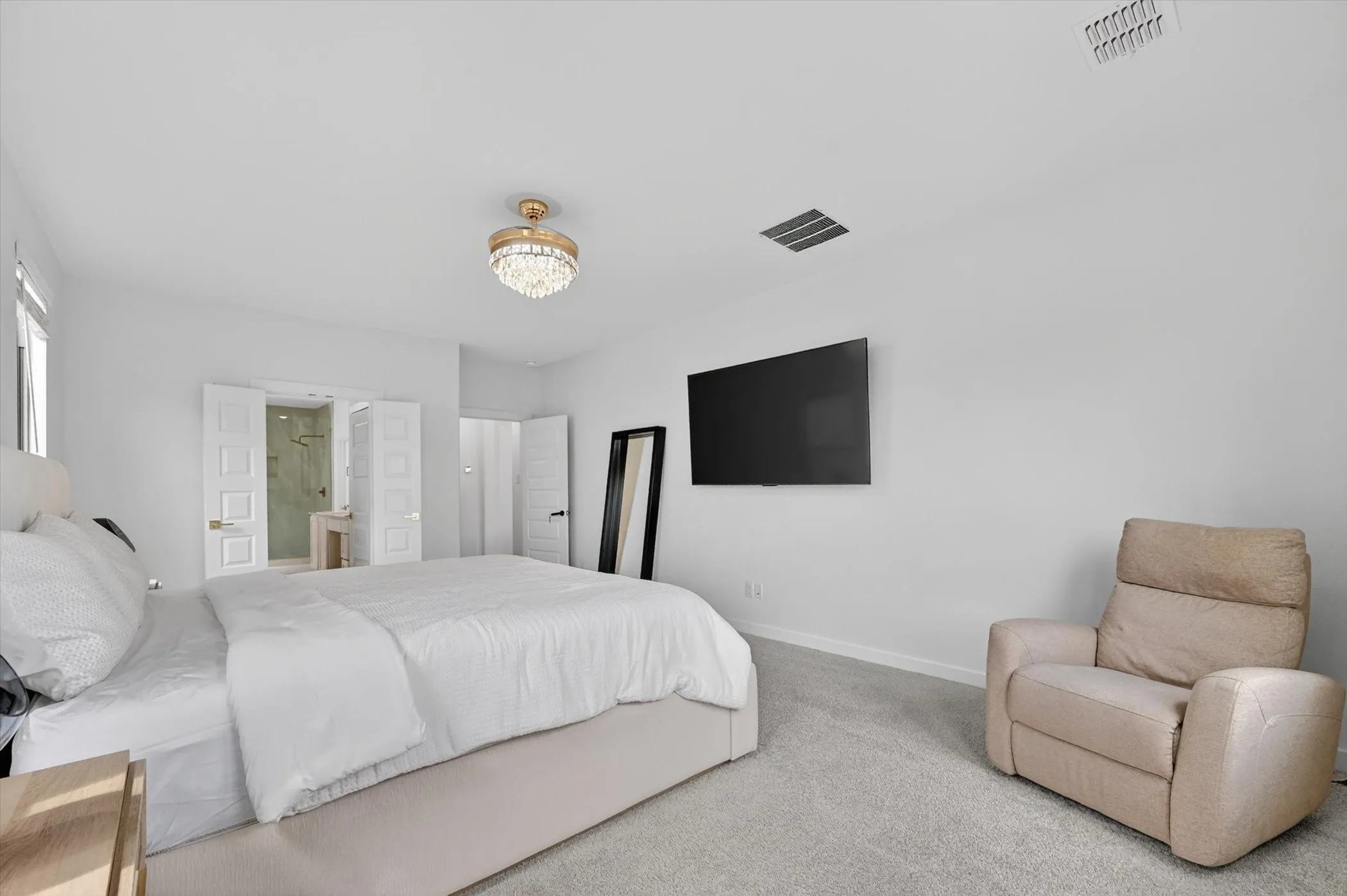 Spacious room featuring light gray carpeting and a decorative ceiling light fixture