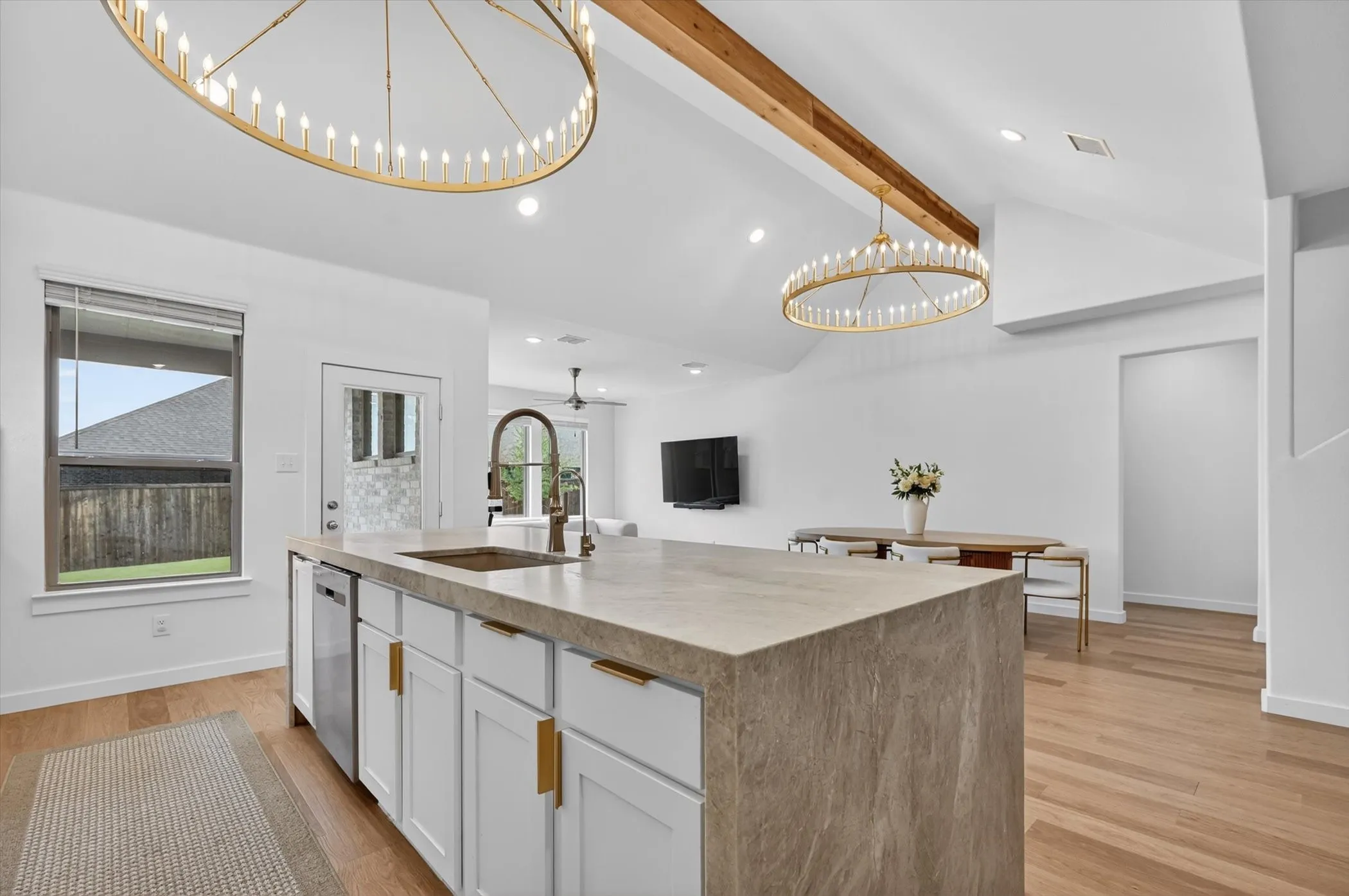 Kitchen island featuring a waterfall-edge countertop, undermount sink, and integrated dishwasher