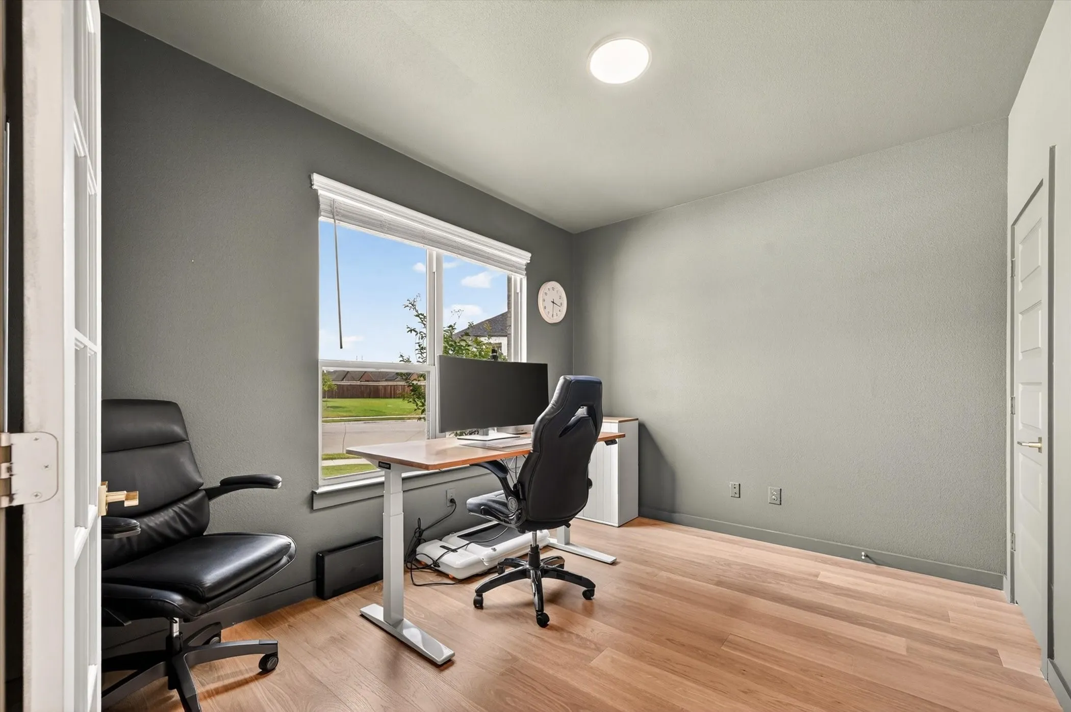 Room featuring wood-finish flooring, a large window, a ceiling-mounted light fixture, and a paneled door