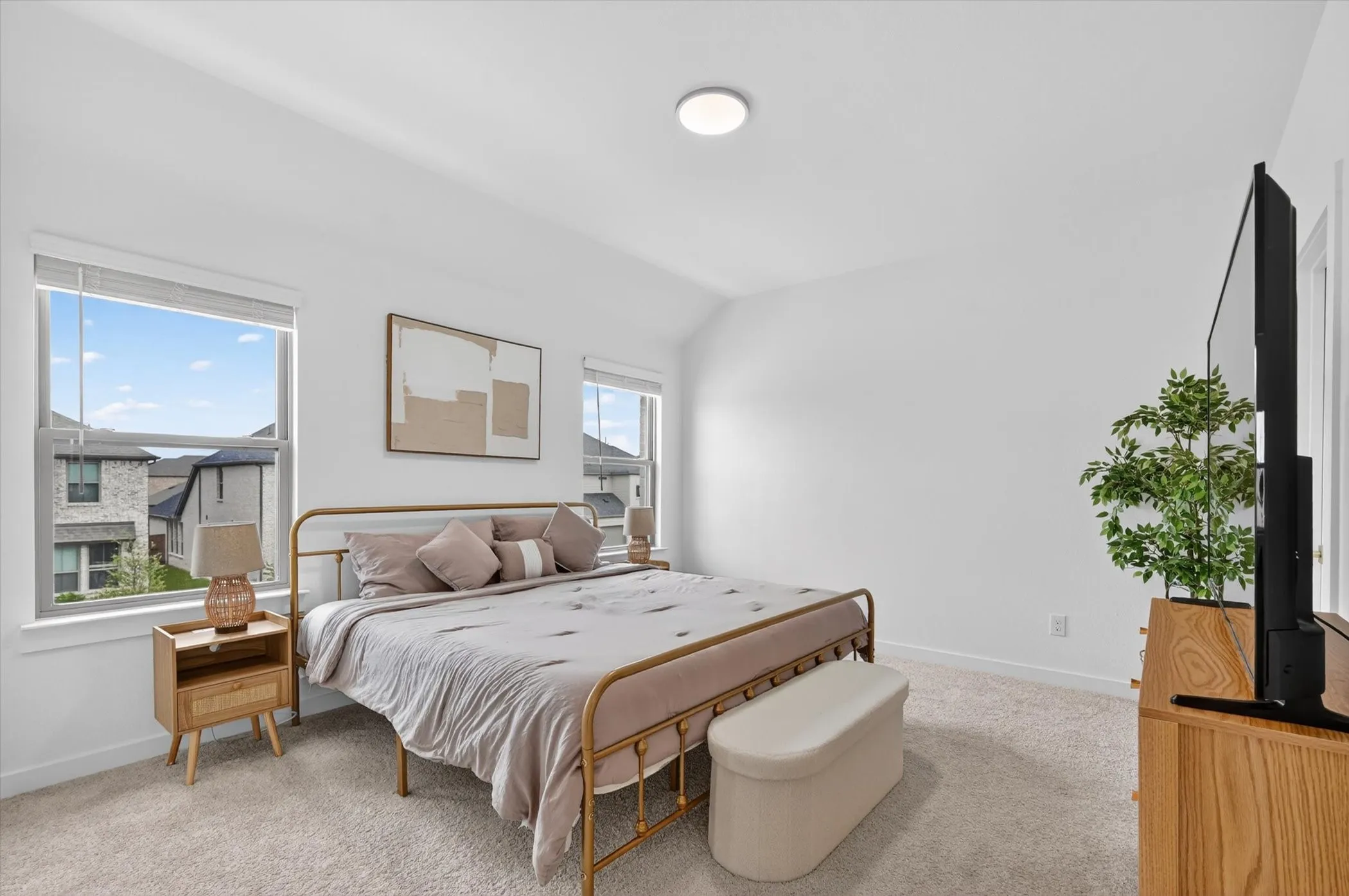 Bright bedroom featuring two large windows, white walls, and light-colored carpeting