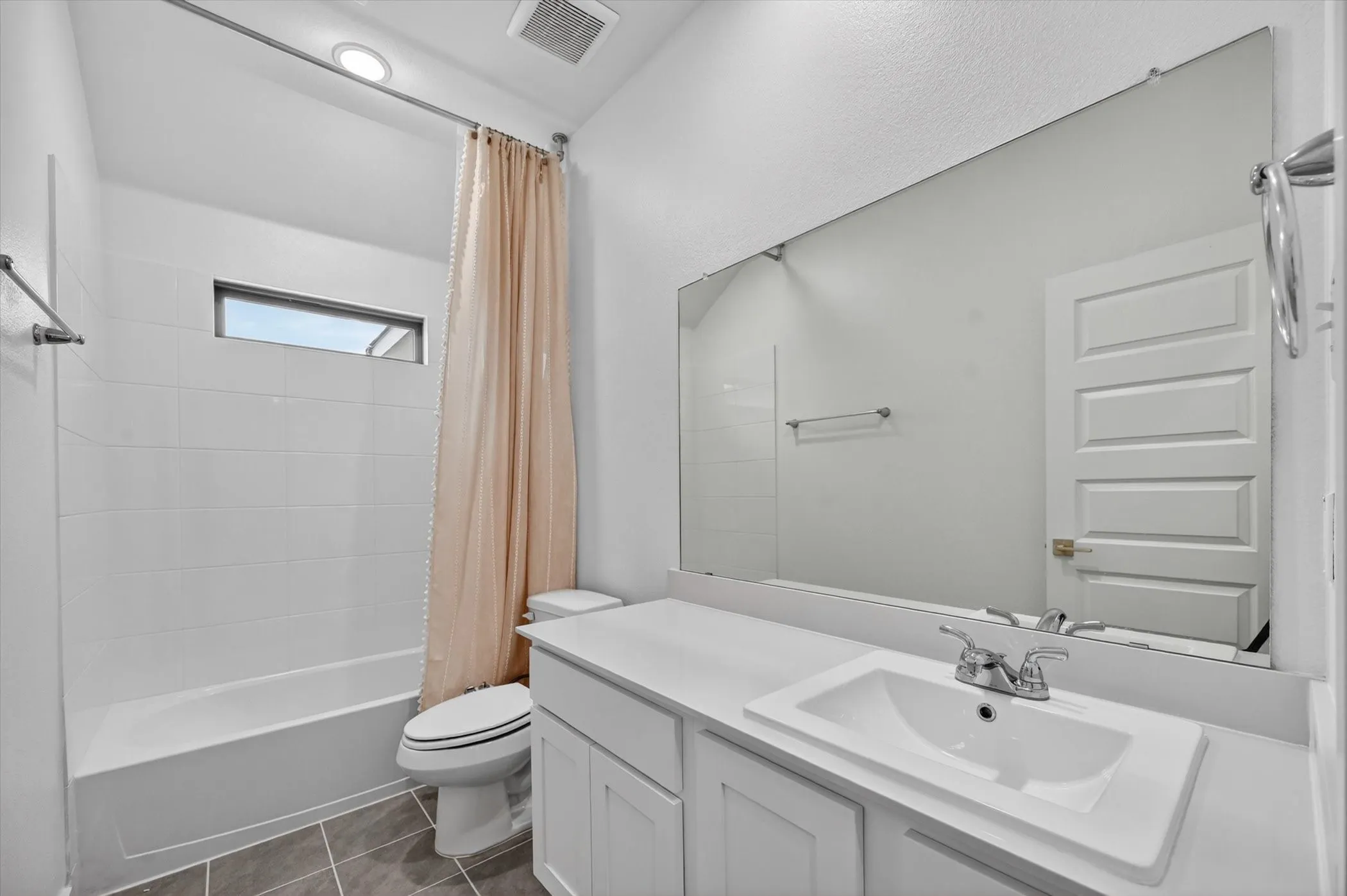 Bathroom featuring a white vanity with an integrated sink, polished chrome faucet, and a large mirror extending to the ceiling