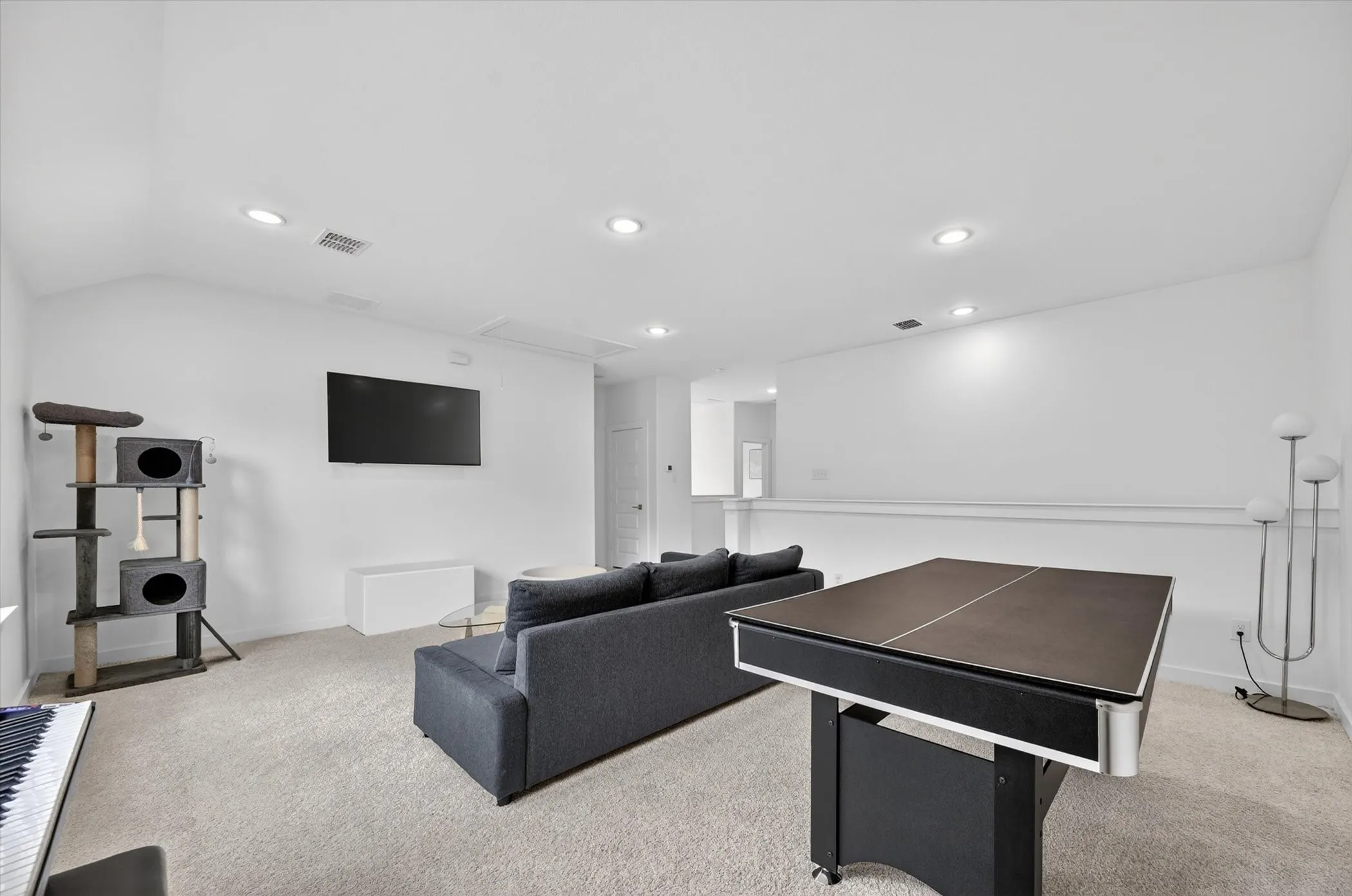 Carpeted room featuring a white wall-mounted television and recessed ceiling lighting
