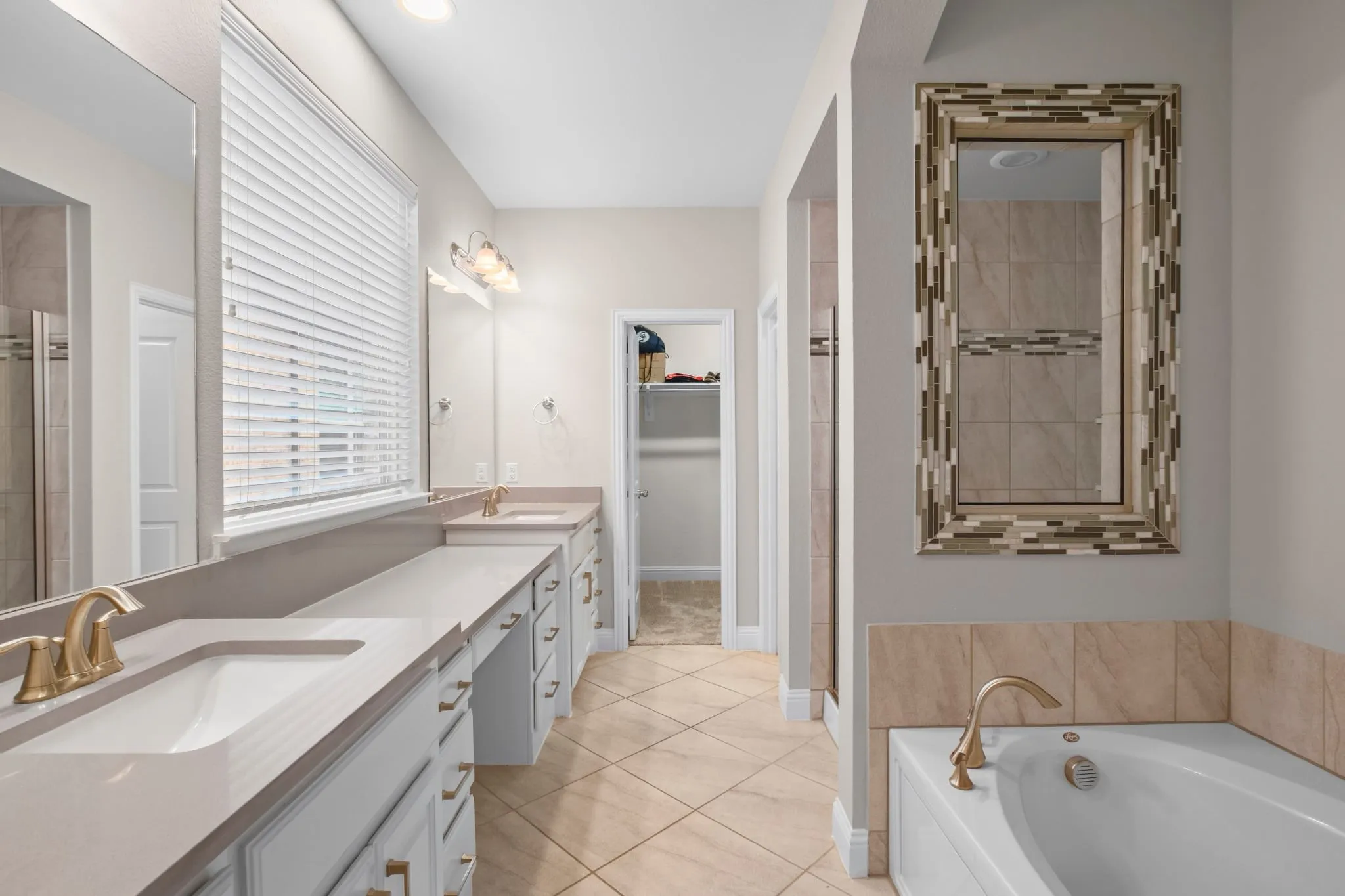 Dual vanity featuring undermount sinks and brass-finish fixtures