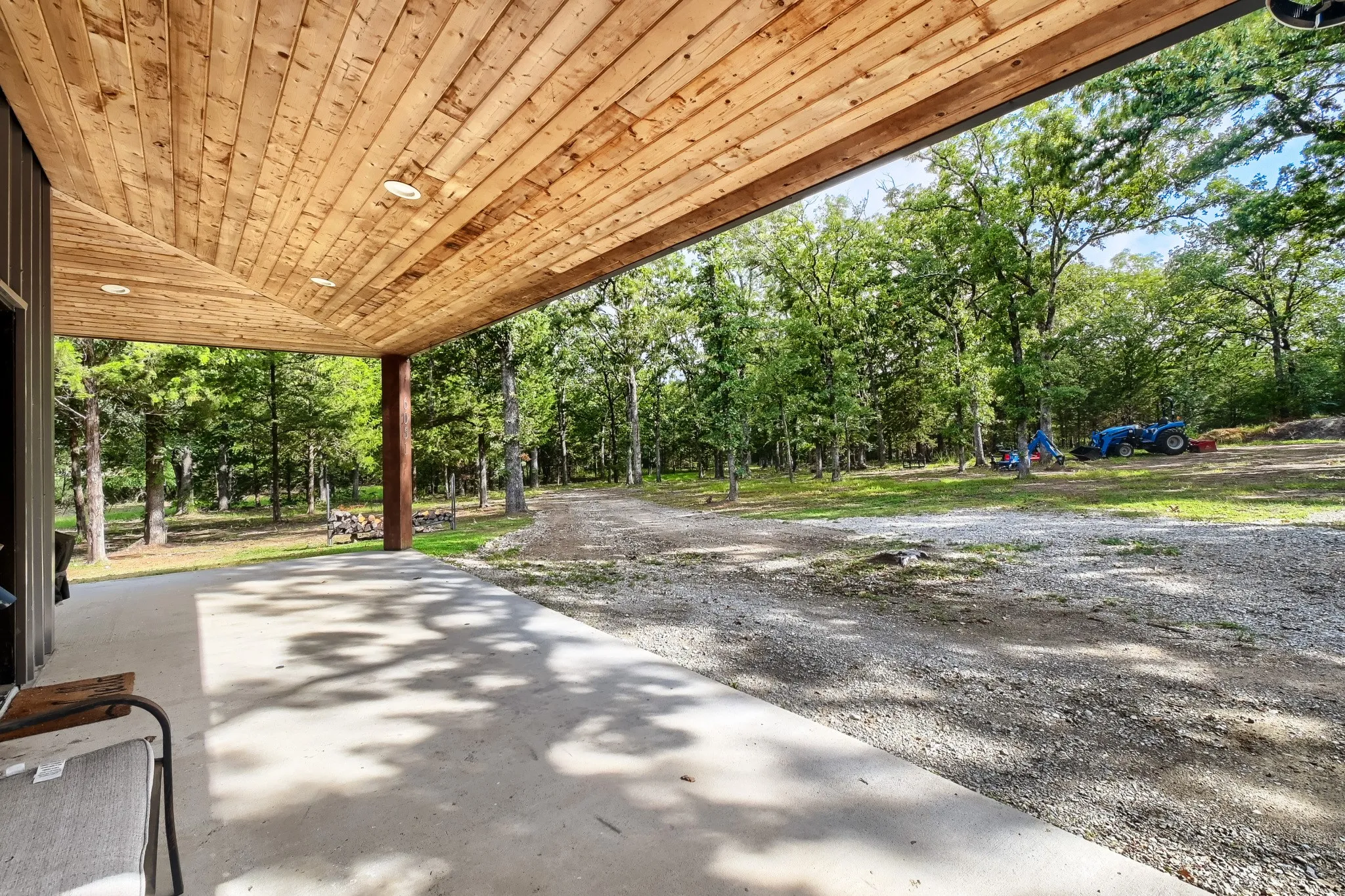 Expansive L-shaped patio featuring a wood-plank ceiling with recessed lighting overlooking 5 acre wooded land.