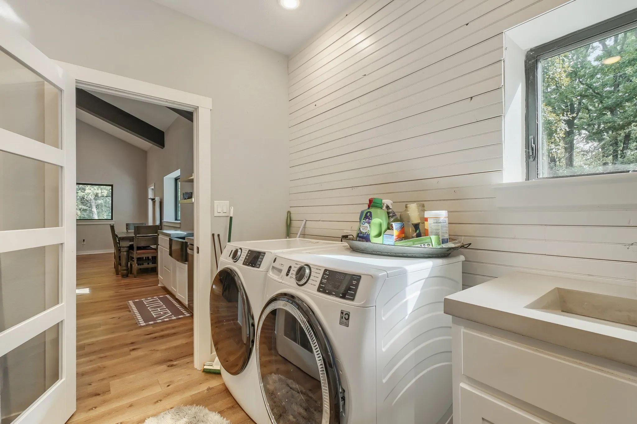Laundry area featuring farmhouse shiplap accent wall, custom-built concrete sink and window overlooking 5 private acres.