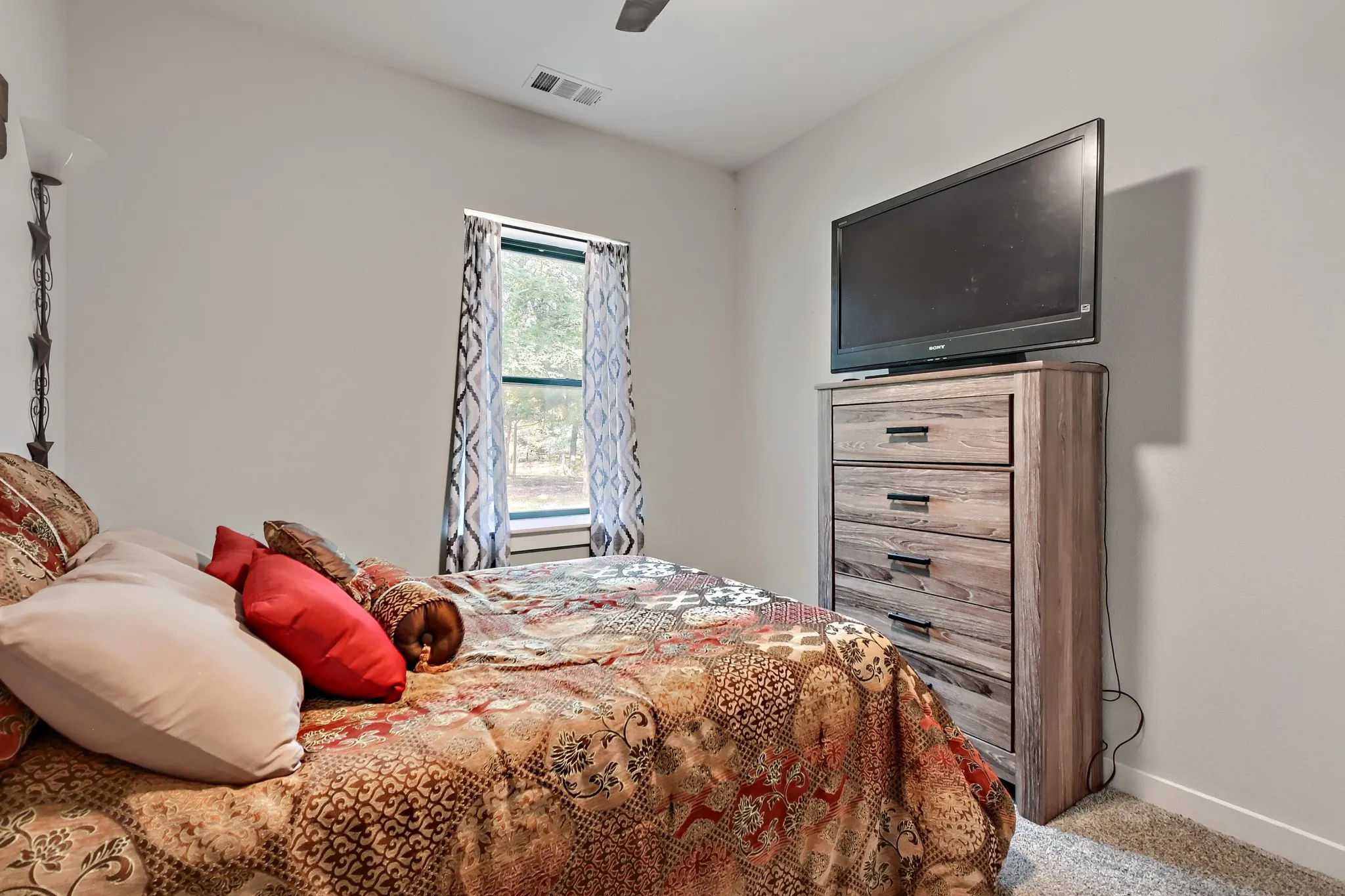 Secondary bedroom featuring a window overlooking 5 private acres with light painted walls and ceiling fan.
