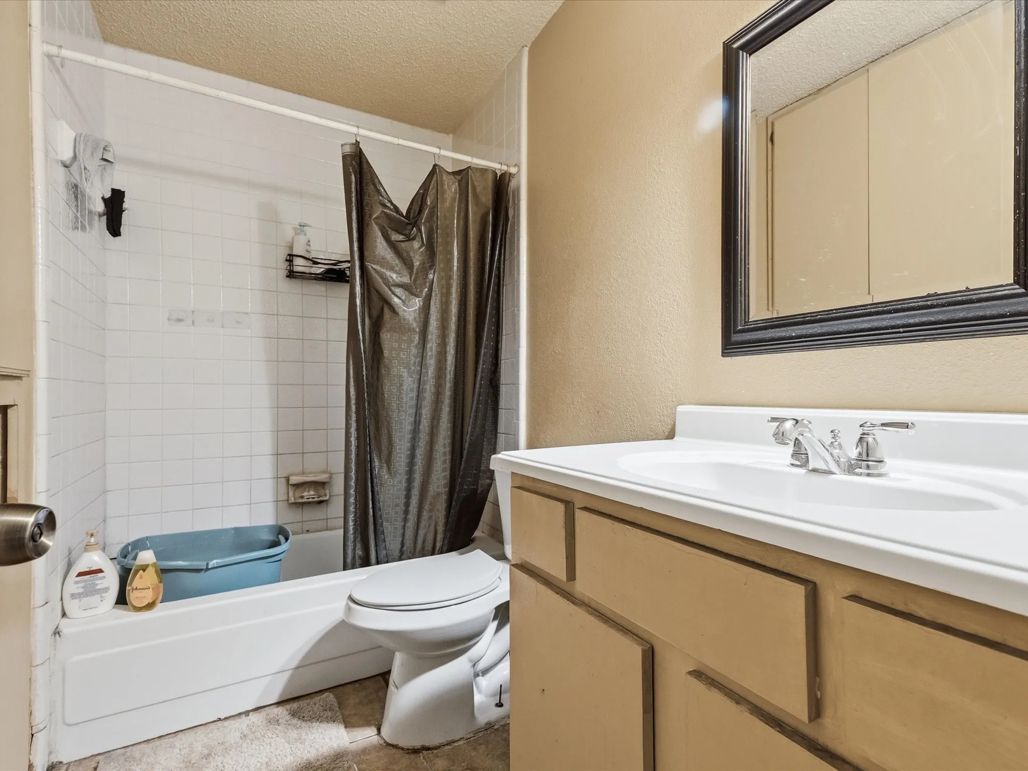 Bathroom featuring a white bathtub, white tile surround, and a vanity with an integrated sink and chrome faucet