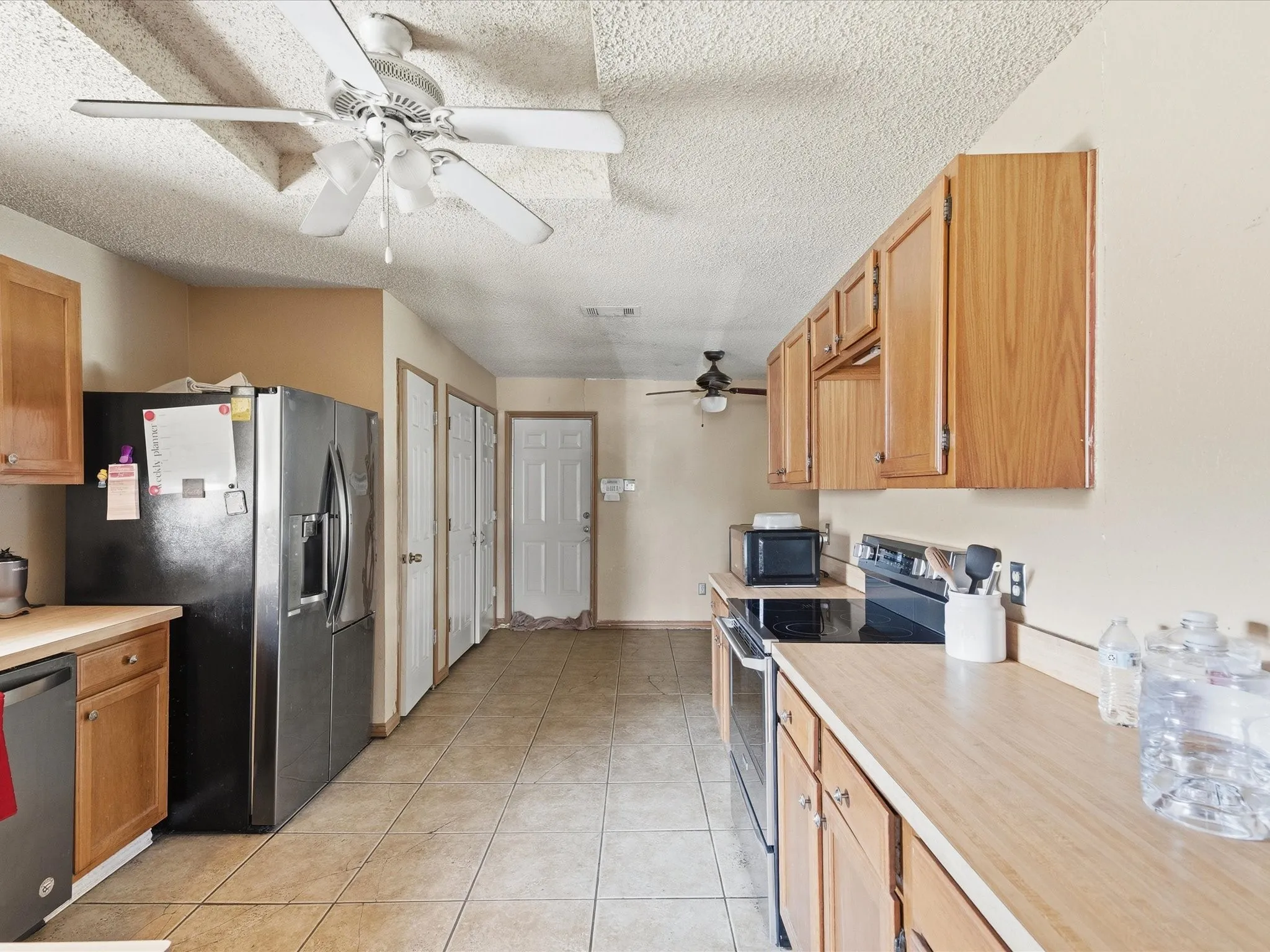 Kitchen area featuring wood-finish cabinetry, tile flooring, and a ceiling fan