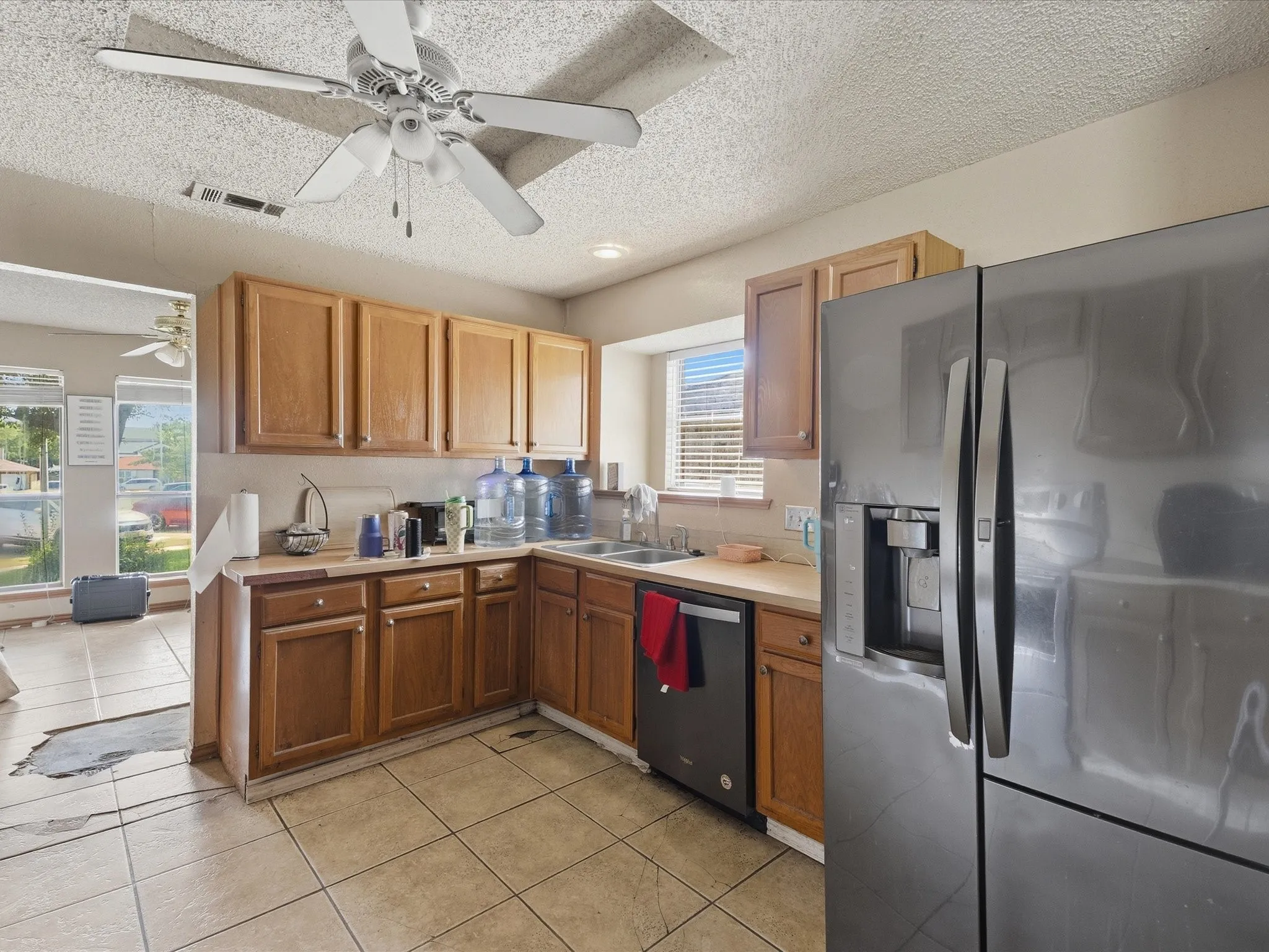 Kitchen featuring wood cabinetry, a stainless steel refrigerator, tile flooring, and a ceiling fan