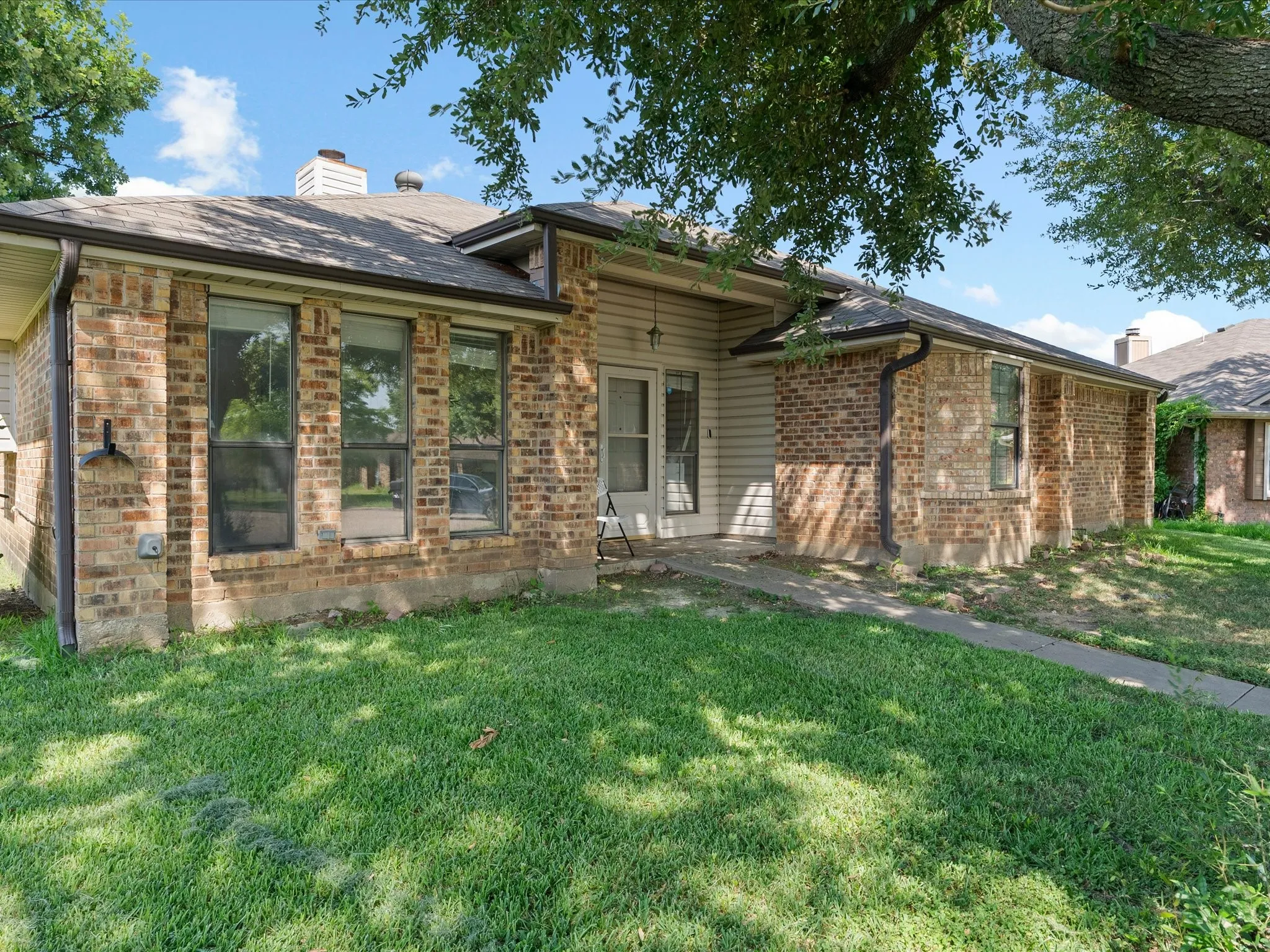Brick and siding exterior with mature trees providing partial shade