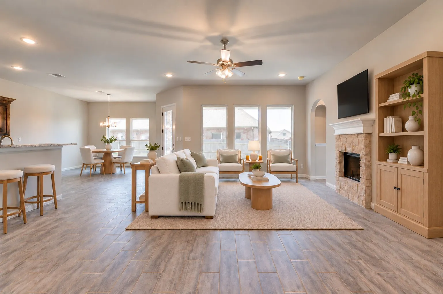 Spacious living area with wood-finish flooring, a stone-faced fireplace, and built-in shelving