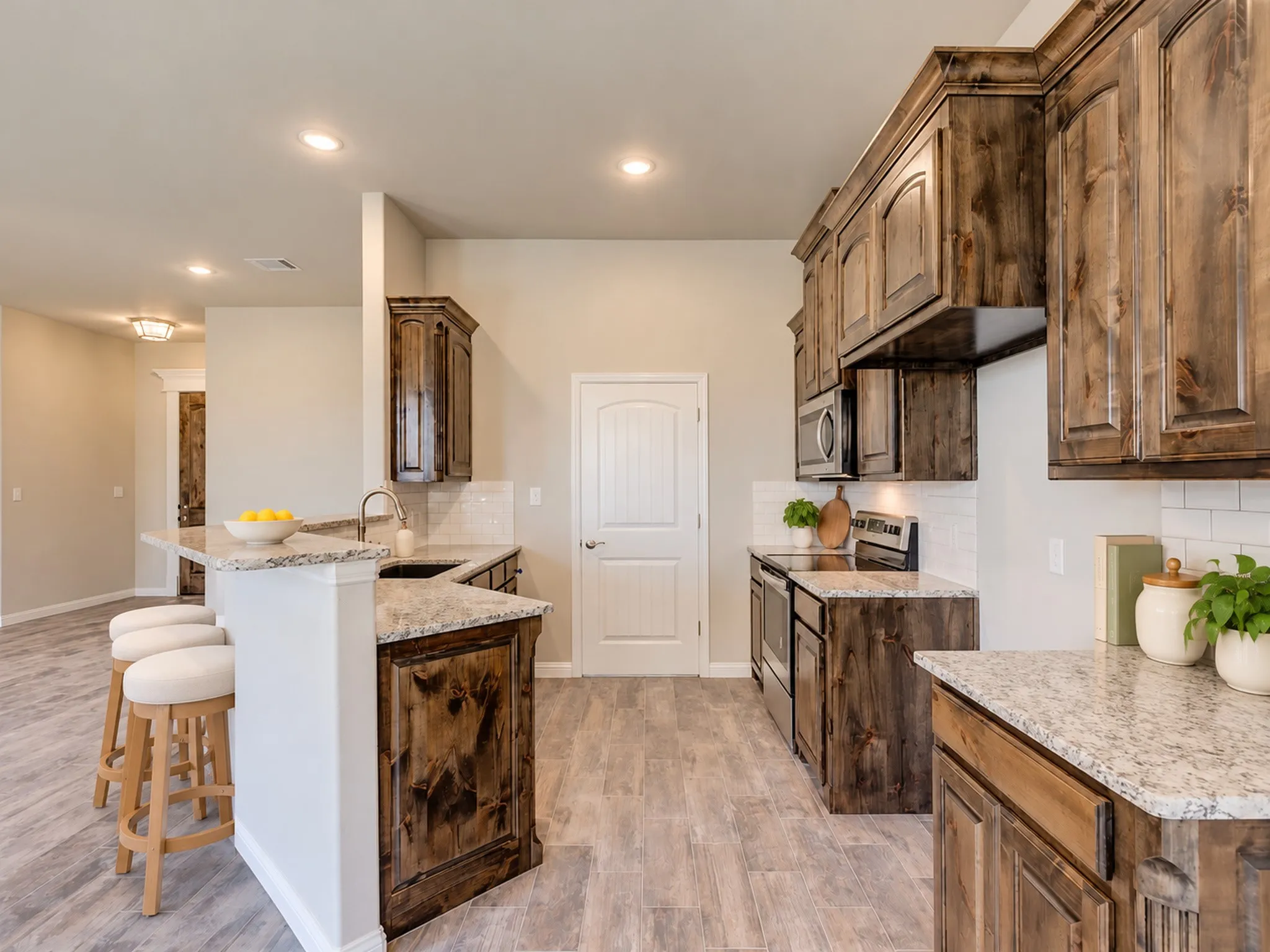 Kitchen featuring wood-finish cabinetry, light-colored countertops, white subway tile backsplash, and stainless steel appliances