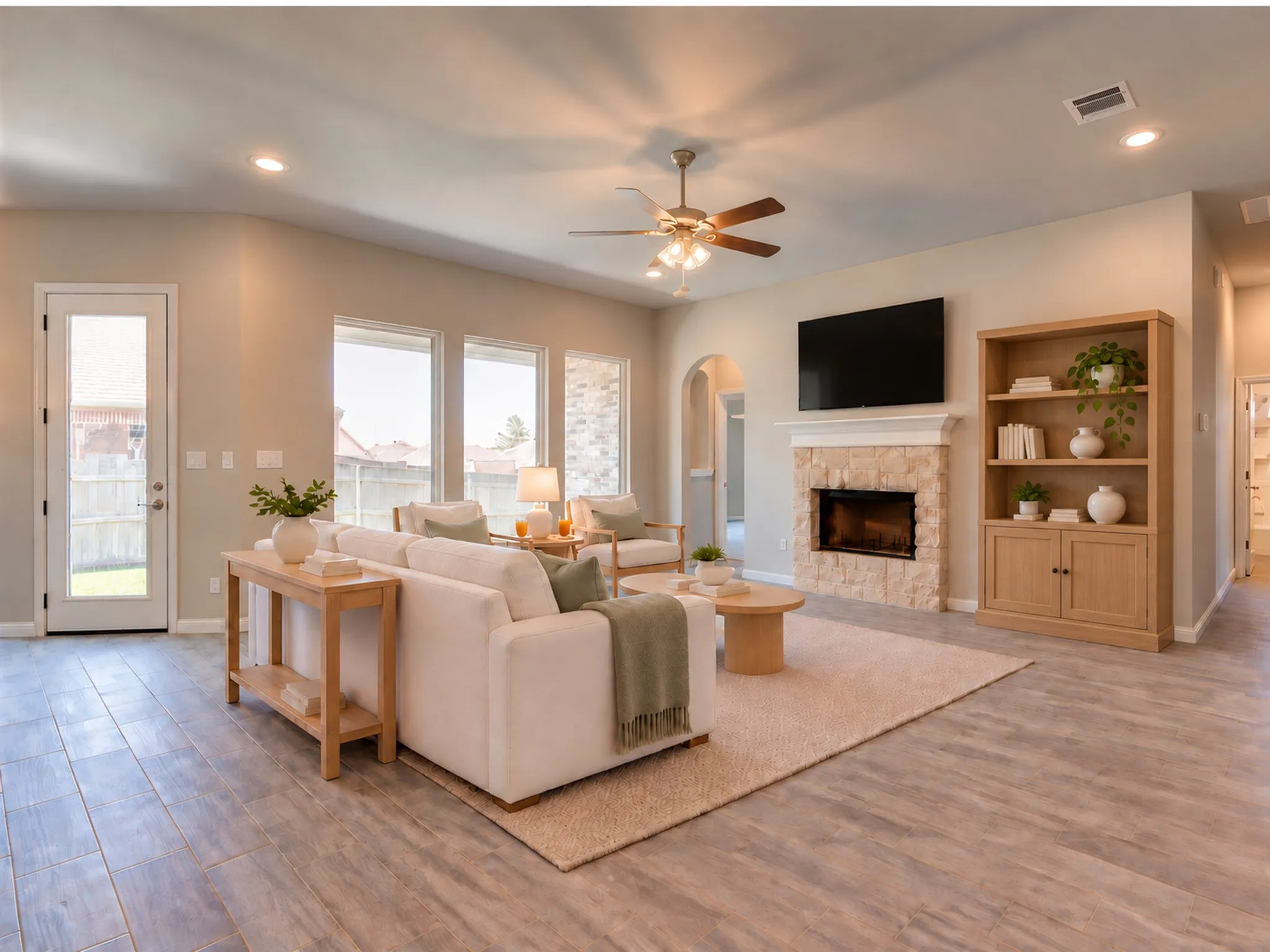 Spacious living area featuring a stone-clad fireplace, wood-finish flooring, recessed lighting, and a ceiling fan