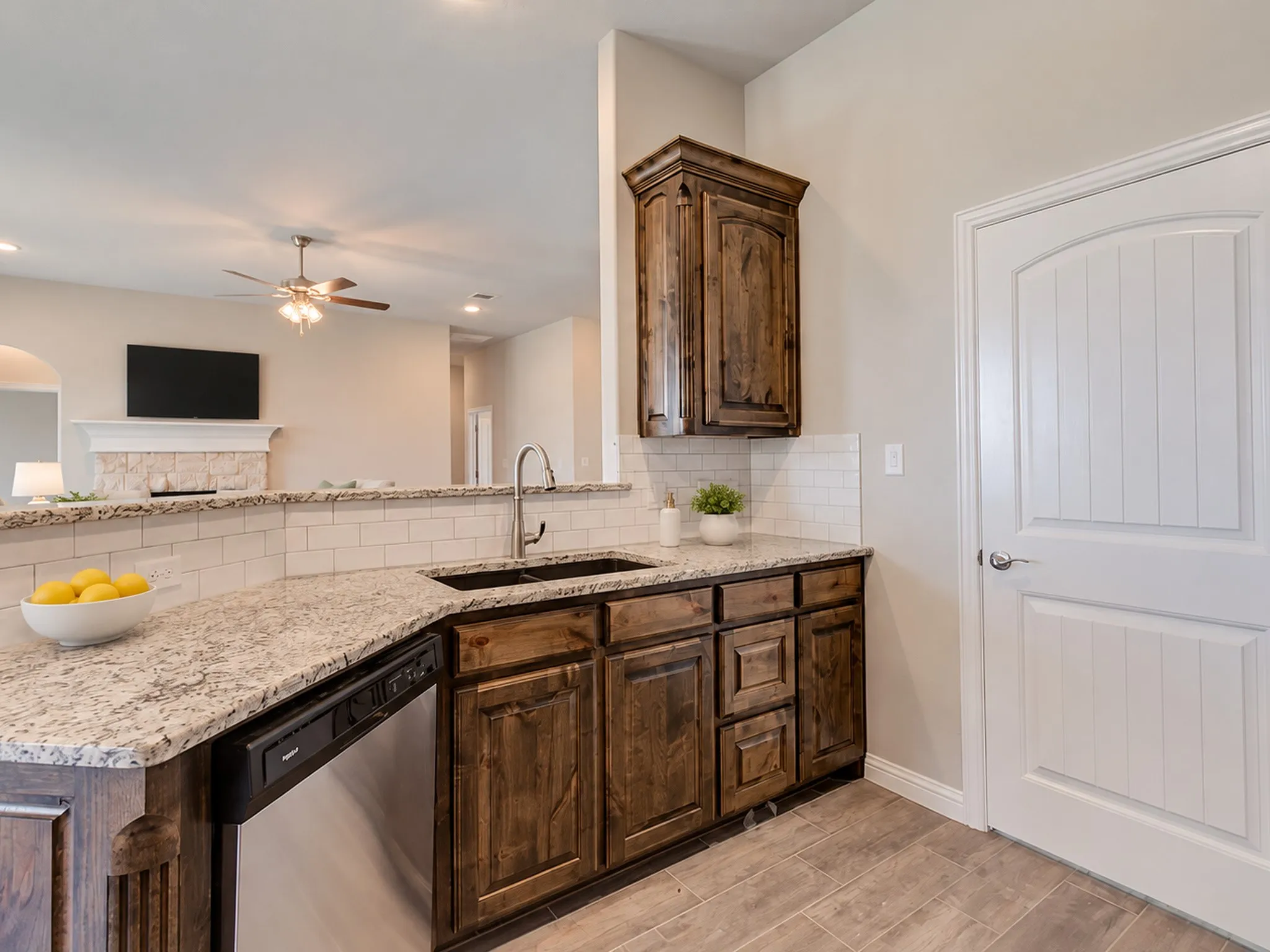 Kitchen with granite countertops, stainless steel sink, wood-finish cabinetry, subway tile backsplash, and tile flooring
