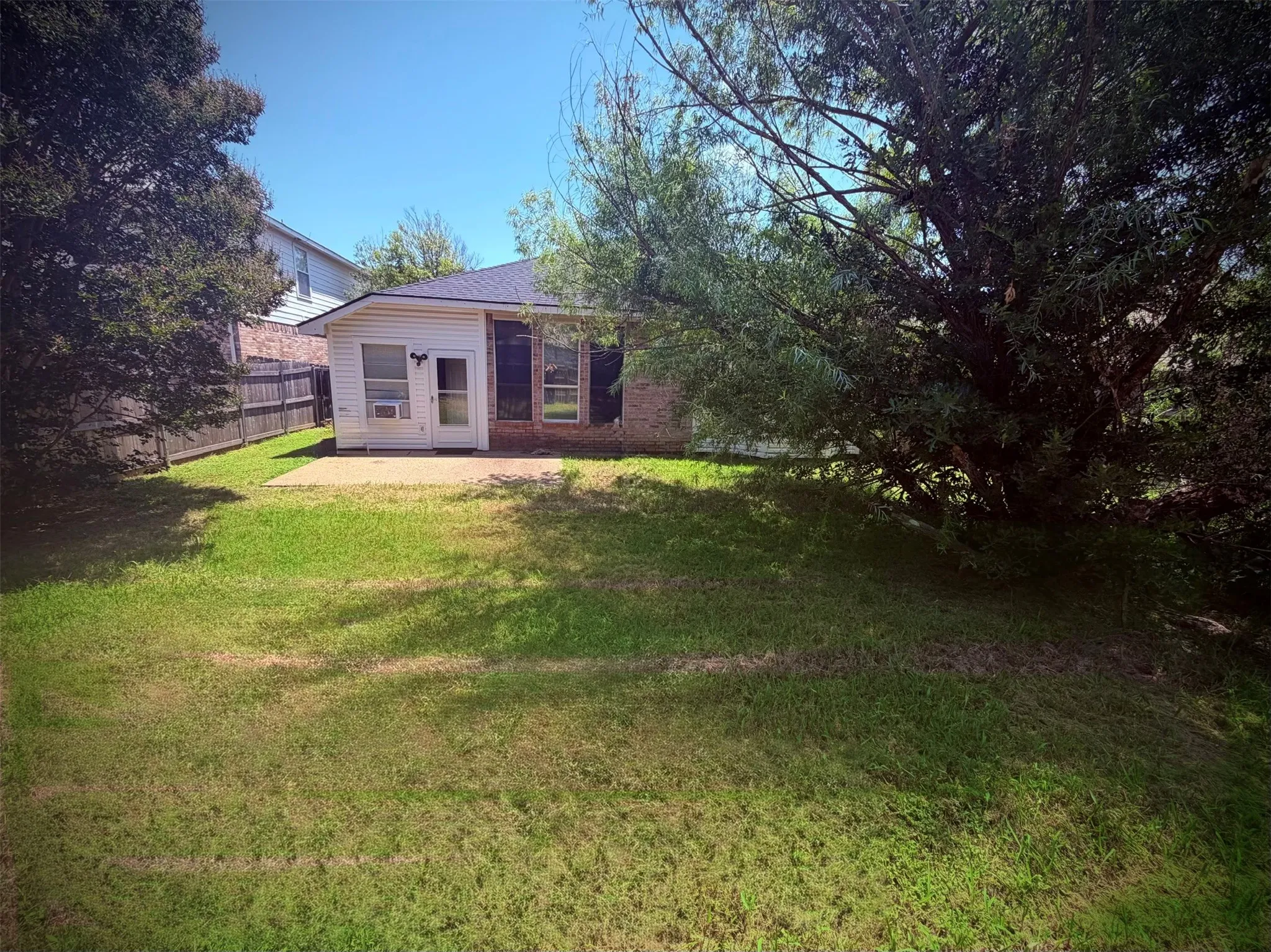 Expansive backyard featuring a concrete patio, a privacy fence, and mature trees