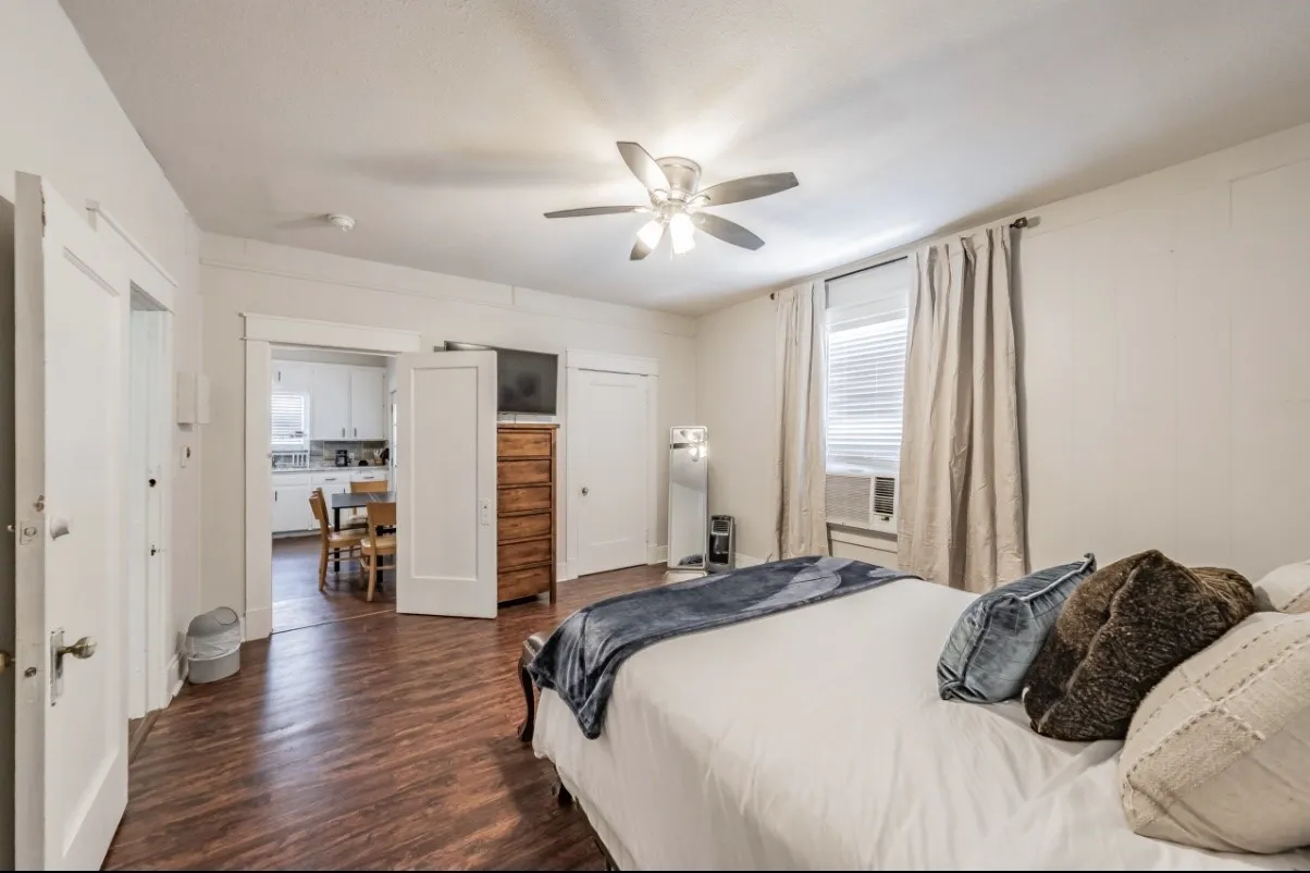 Spacious room featuring wood-finish flooring, a ceiling fan, and white trim molding