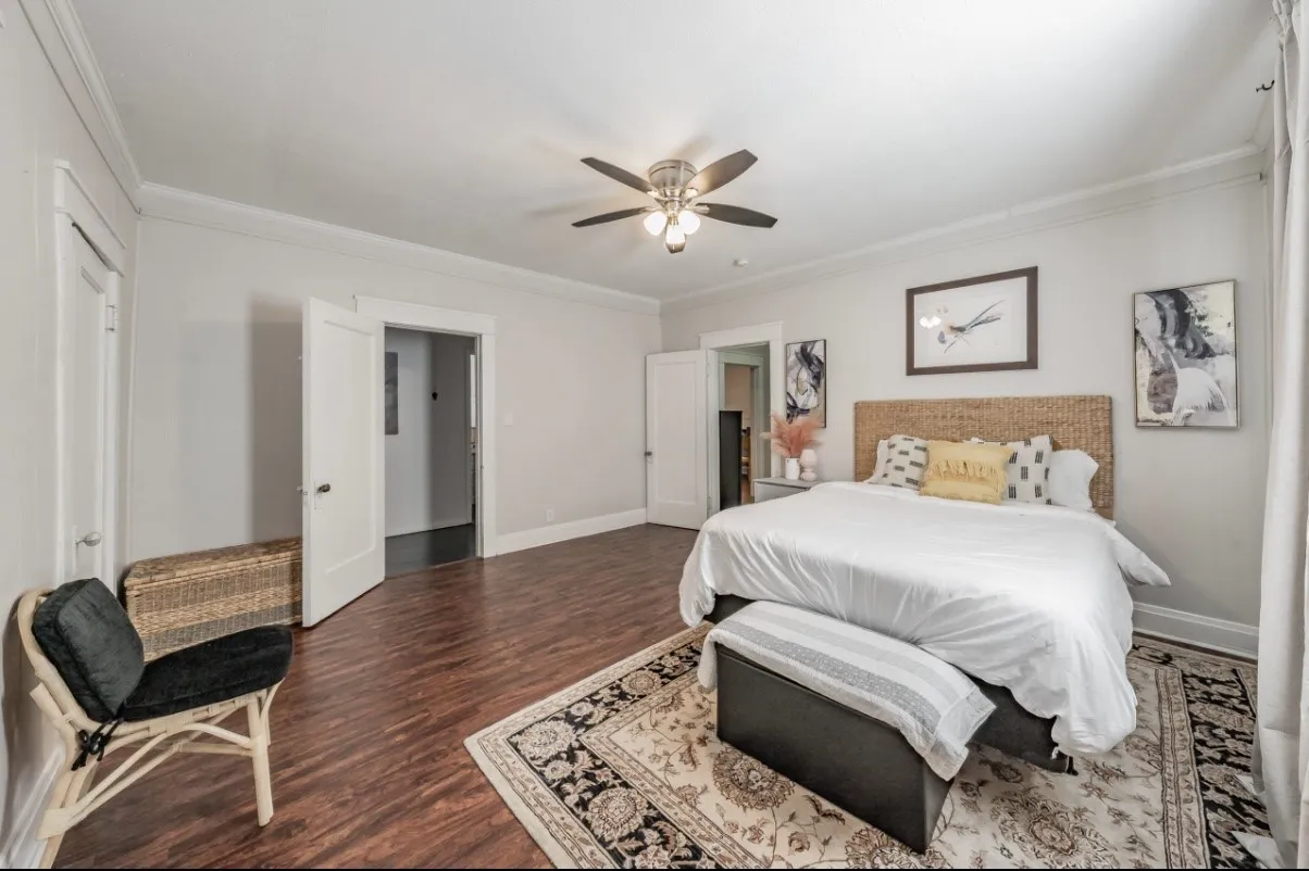Spacious room with wood-finish flooring, two panel doors, and a ceiling fan with integrated lighting