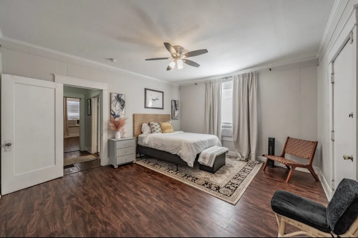 Spacious room featuring wood-finish flooring, a ceiling fan, and crown molding