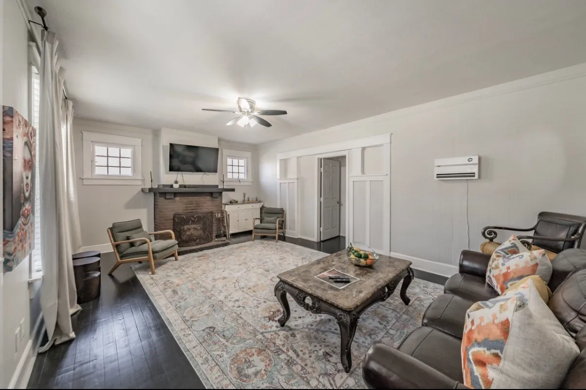 Living area featuring dark wood-finish flooring, a brick fireplace with a wood mantle, and white trim