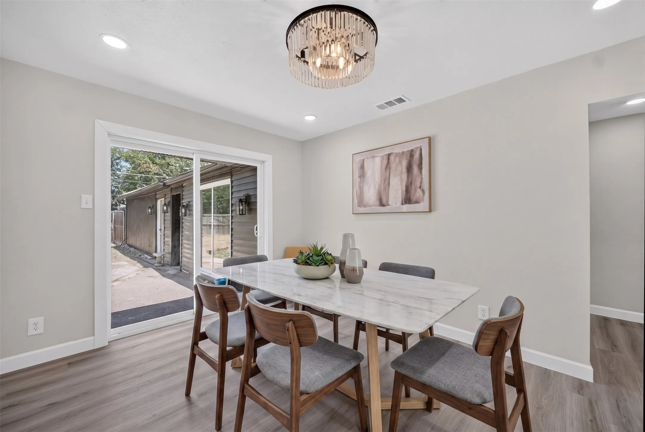 Dining area featuring wood-finish flooring, light gray wall paint, and a modern chandelier