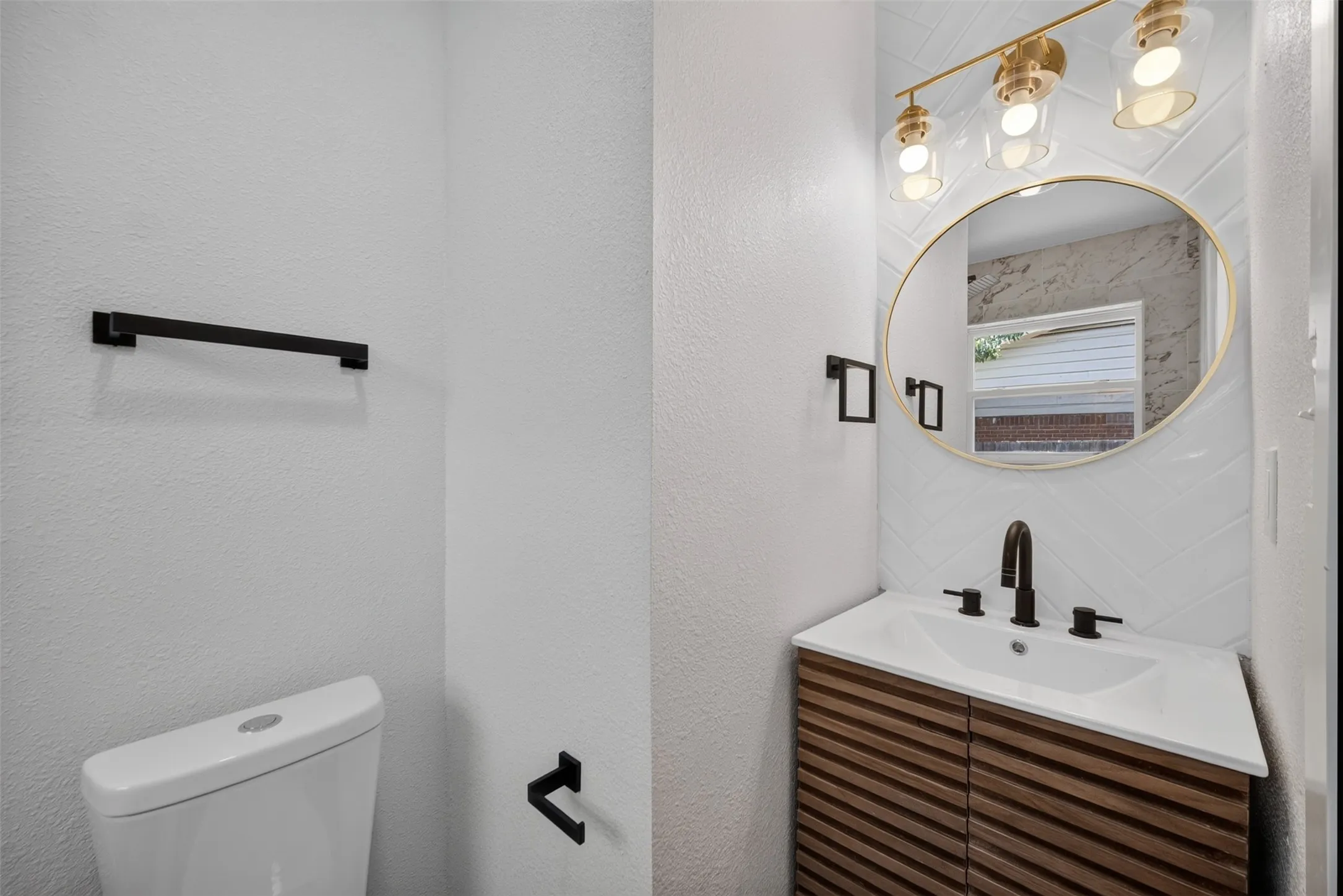 Vanity with wood-finish cabinetry, integrated sink, and matte black faucet