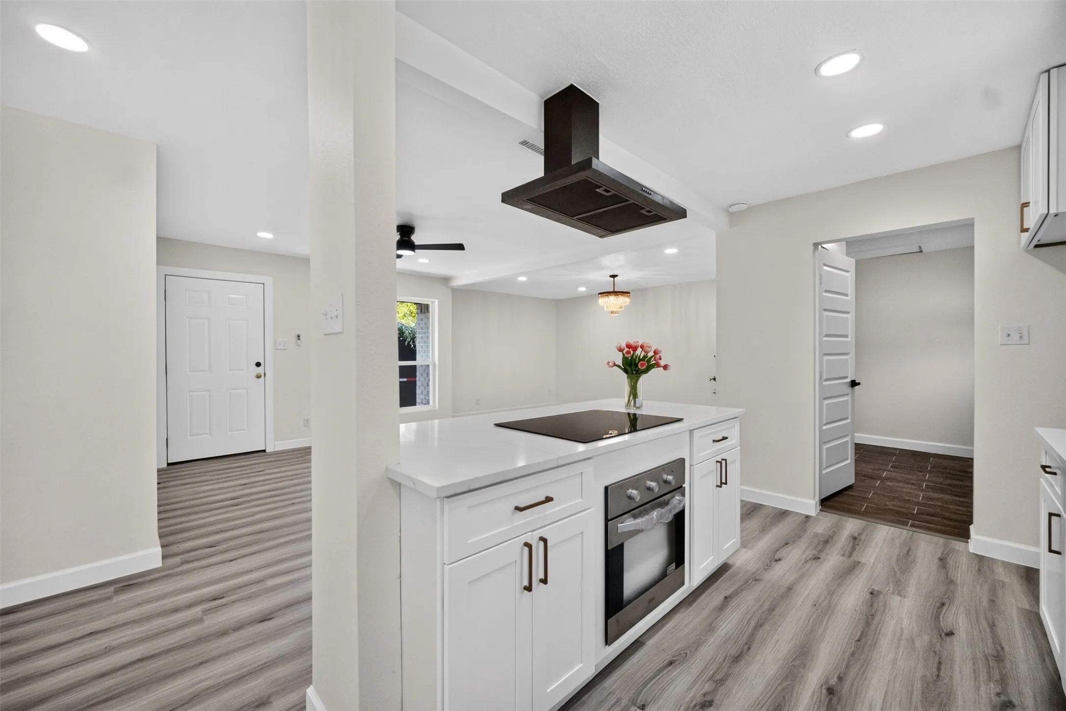 Kitchen island with an integrated cooktop, built-in oven, and white countertop