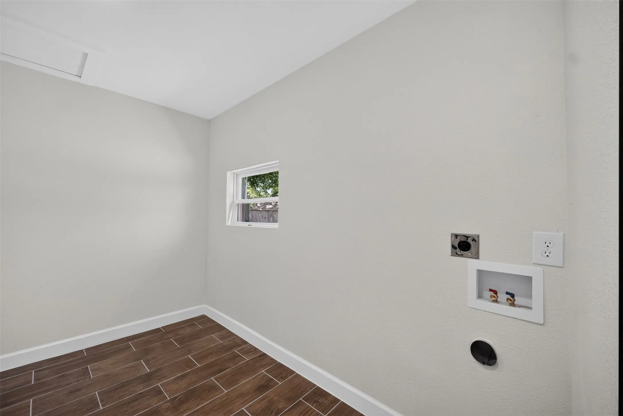 Utility room featuring wood-finish tile flooring, a single window, and white baseboards