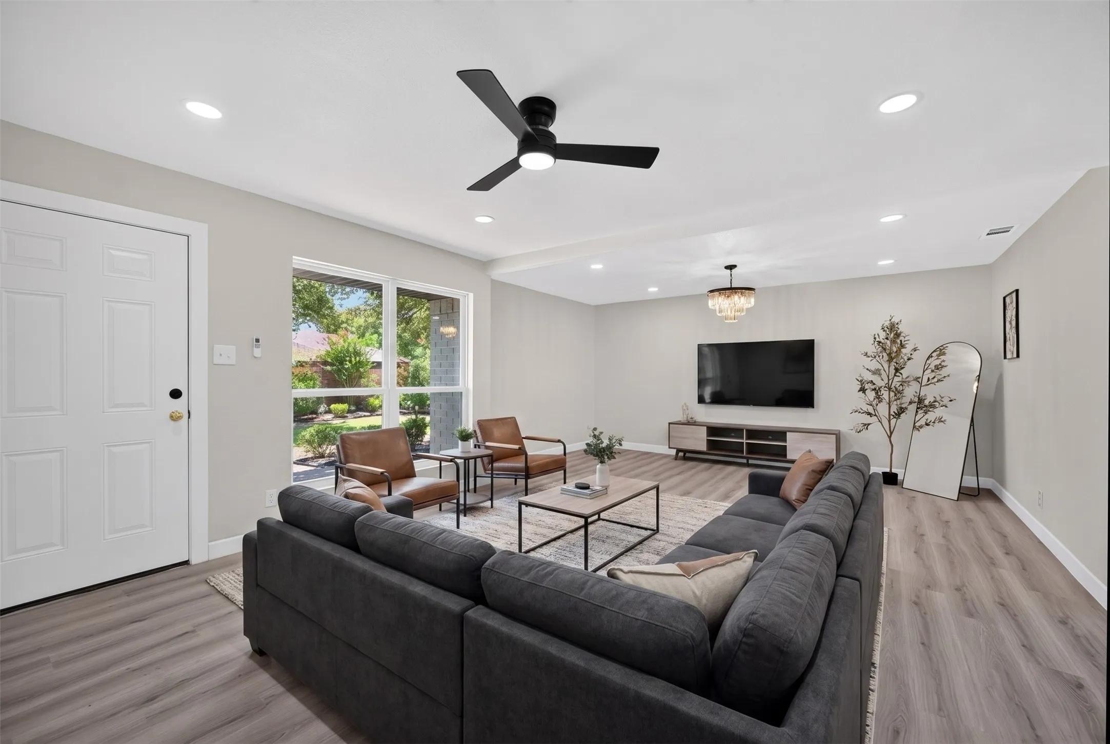 Spacious interior room featuring light-toned walls, wood-finish flooring, and recessed lighting