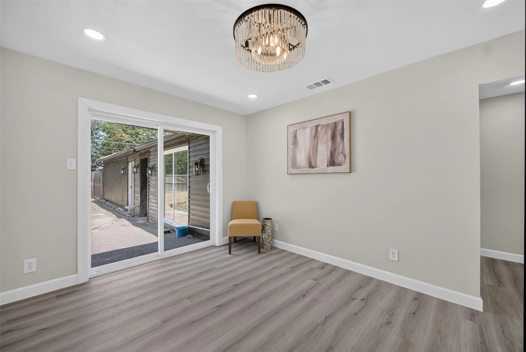 Spacious room featuring wood-finish flooring, recessed lighting, and a modern chandelier