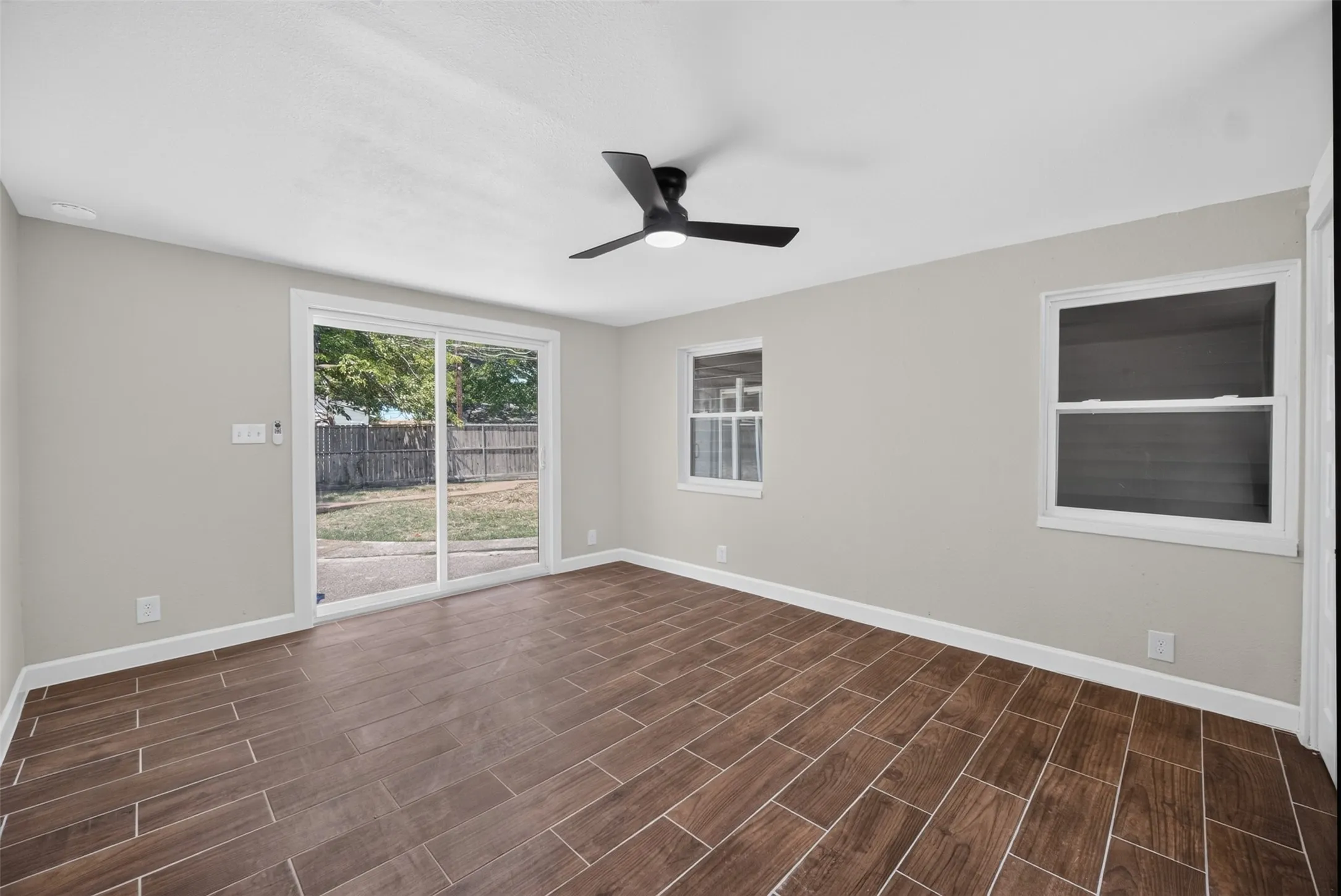 Spacious interior featuring wood-look tile flooring, light gray wall paint, and white trim