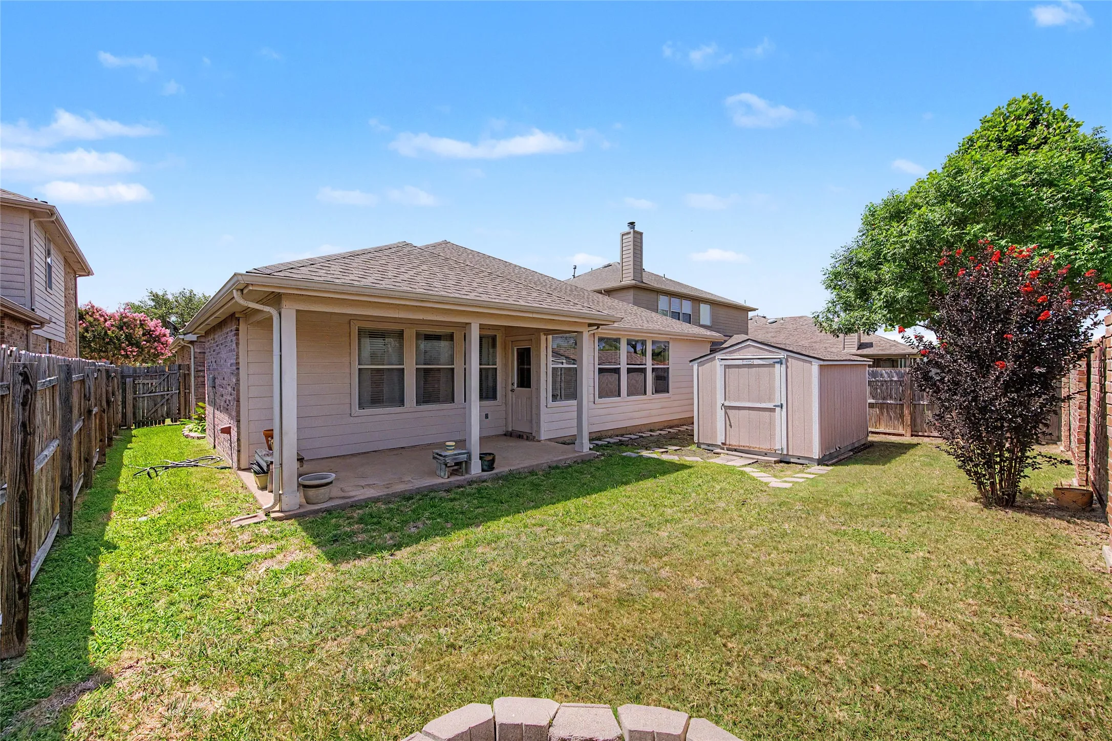 Expansive backyard with a covered patio, manicured lawn, and mature trees
