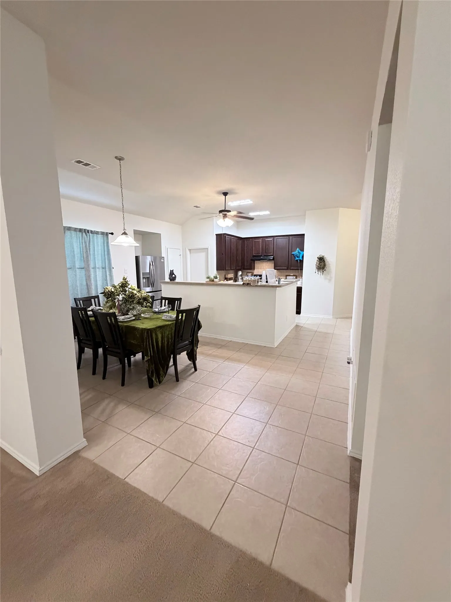 Open-concept living space with vaulted ceilings, recessed lighting, tile flooring, and dark wood-finish cabinetry