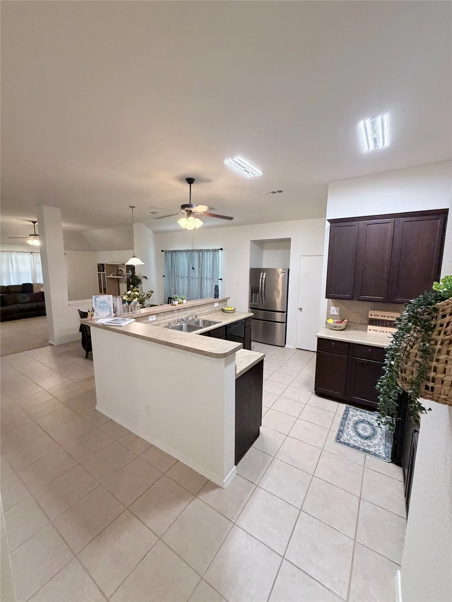 Kitchen featuring tile flooring, dark wood-finish cabinetry, stainless steel refrigerator, and recessed lighting