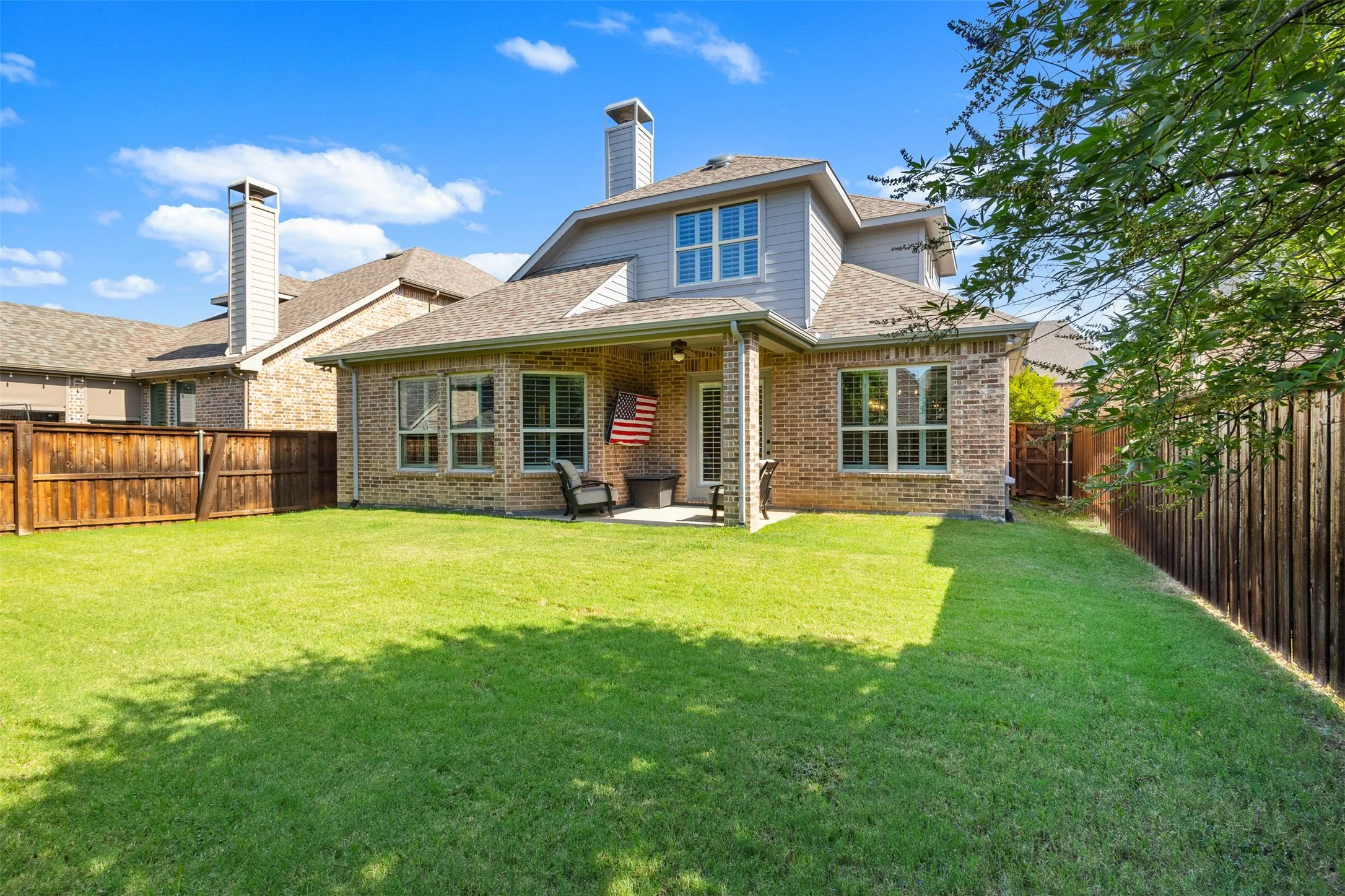 Spacious backyard featuring a manicured lawn, full privacy fencing, and a covered patio