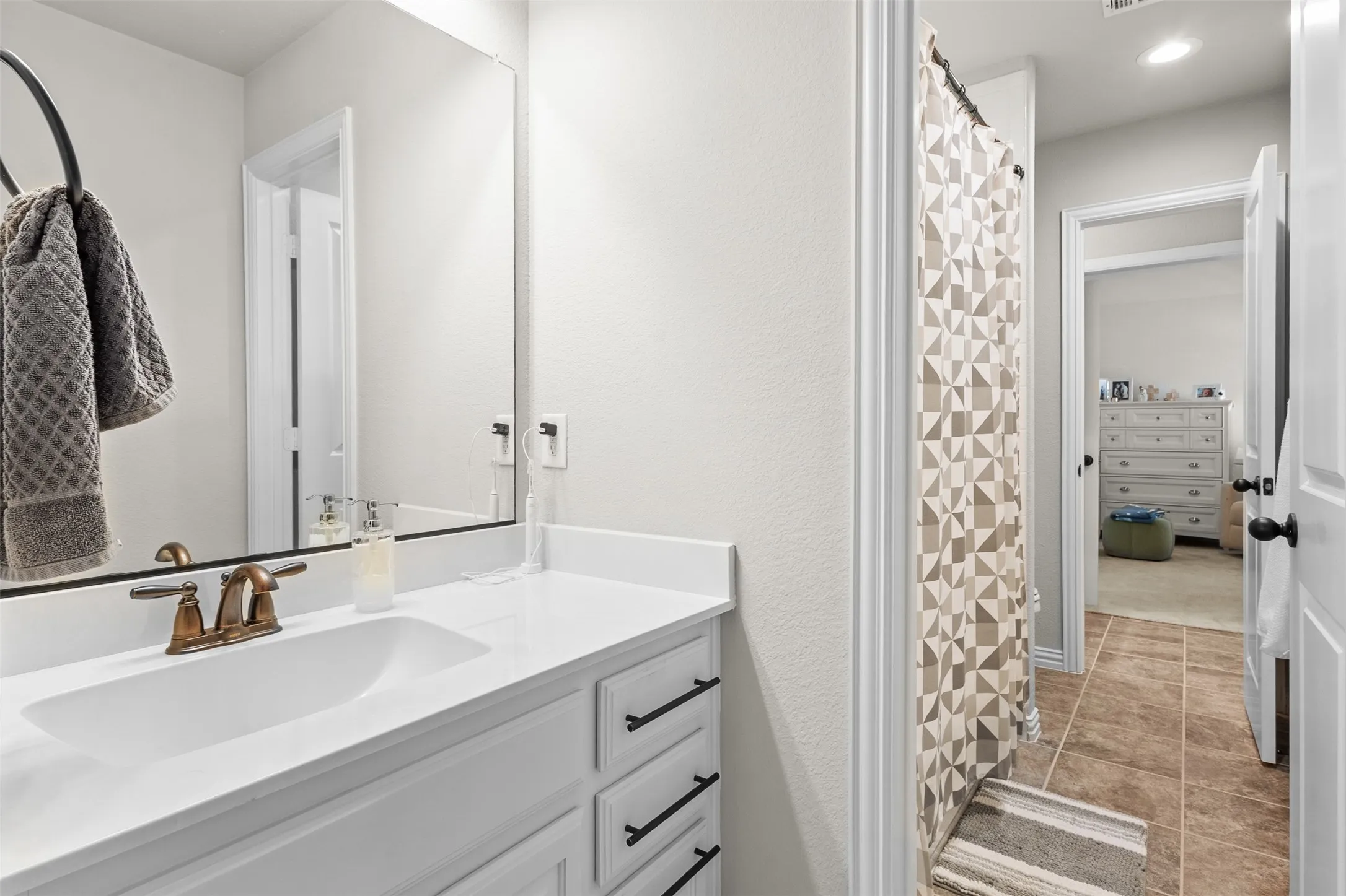 Bathroom vanity featuring a white countertop with an integrated sink, bronze-finish faucet, and white cabinetry with matte black hardware