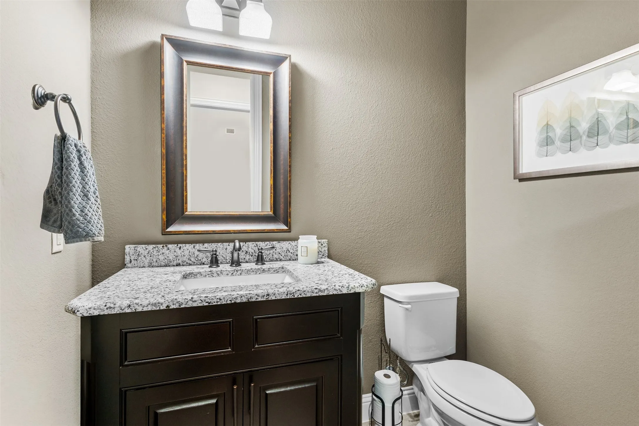 Powder room featuring a dark wood vanity with a granite-style countertop, undermount sink, and dark bronze faucet
